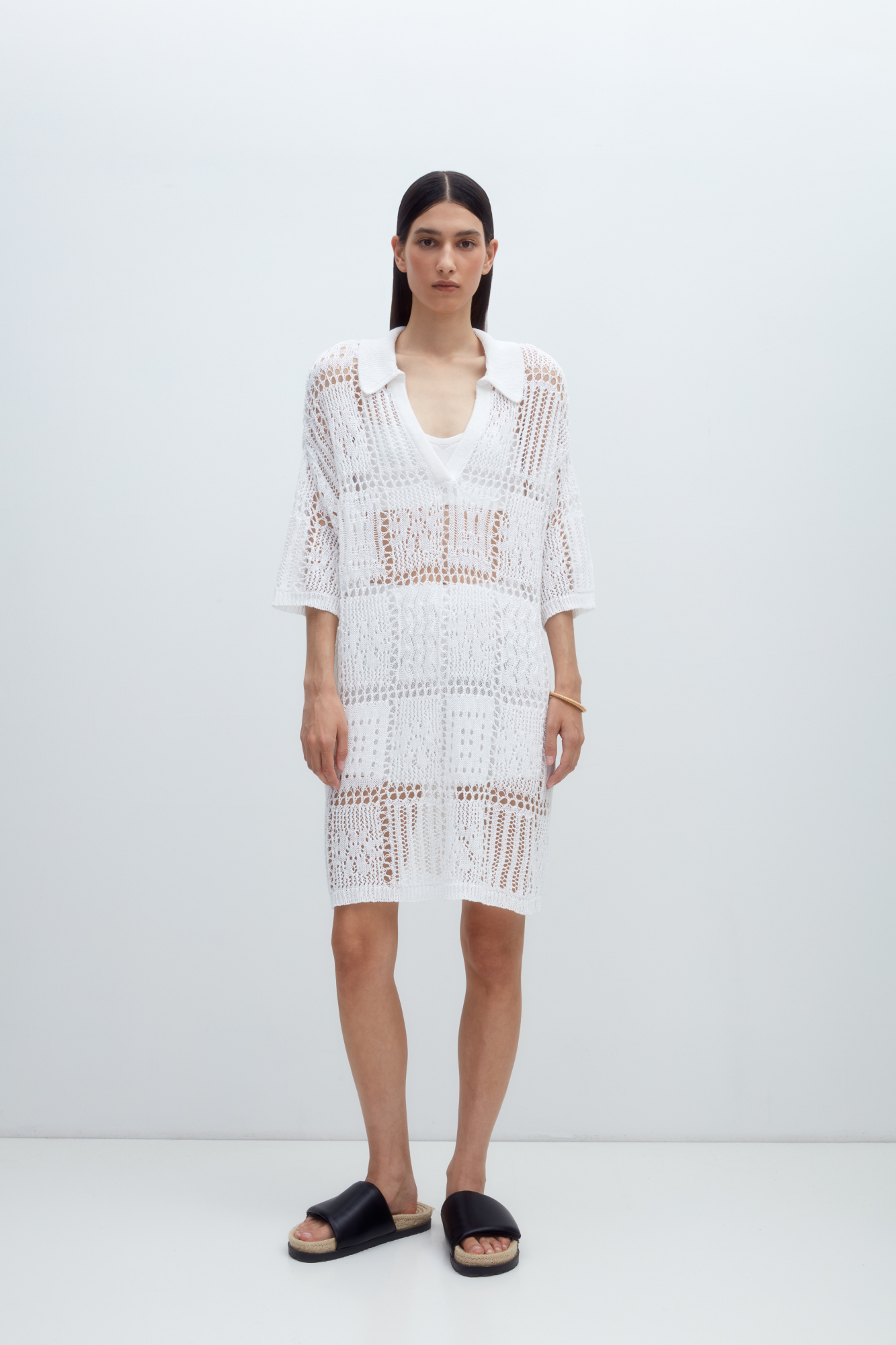 Трикотажный комплект из 100% льна, состоящий из платья длины мини и шорт. Ажурное платье со спущенной линией плеч, рукавом 3/4, V-образным вырезом и отложным воротником. Шорты прямого кроя с эластичным поясом. Края изделия выполнены в рубчик. 