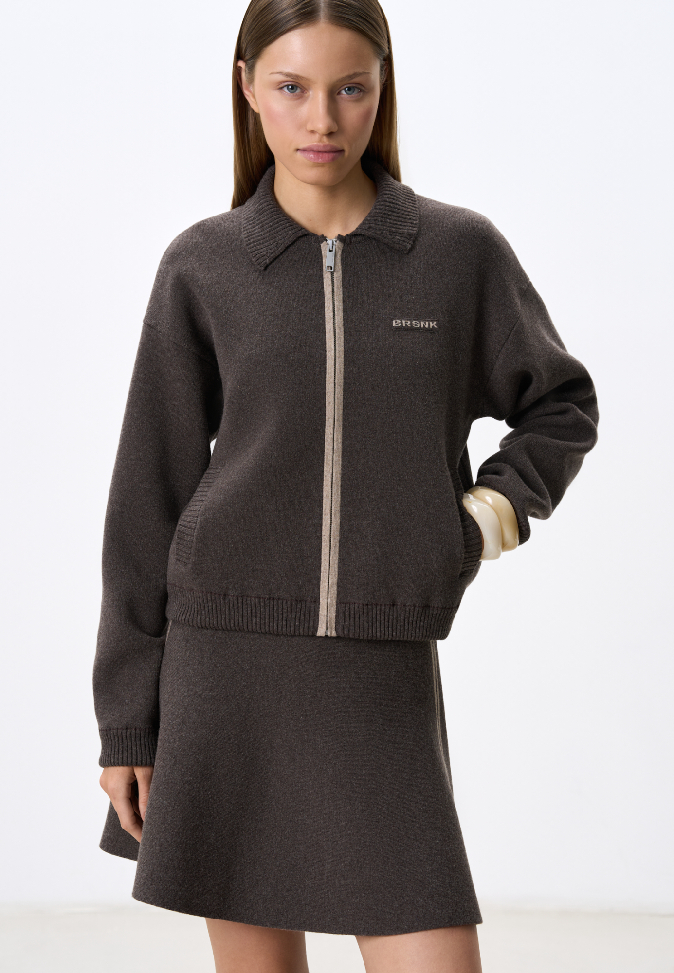 Трикотажный бомбер из кашемира и шерсти. Модель свободного силуэта, со спущенной линией плеч, отложным воротником, боковыми карманами, застежкой на молнию, планкой контрастного цвета и брендированным жаккардом на груди. Низ изделия выполнен на резинке. Дополнить образ можно юбкой в таком же стиле.