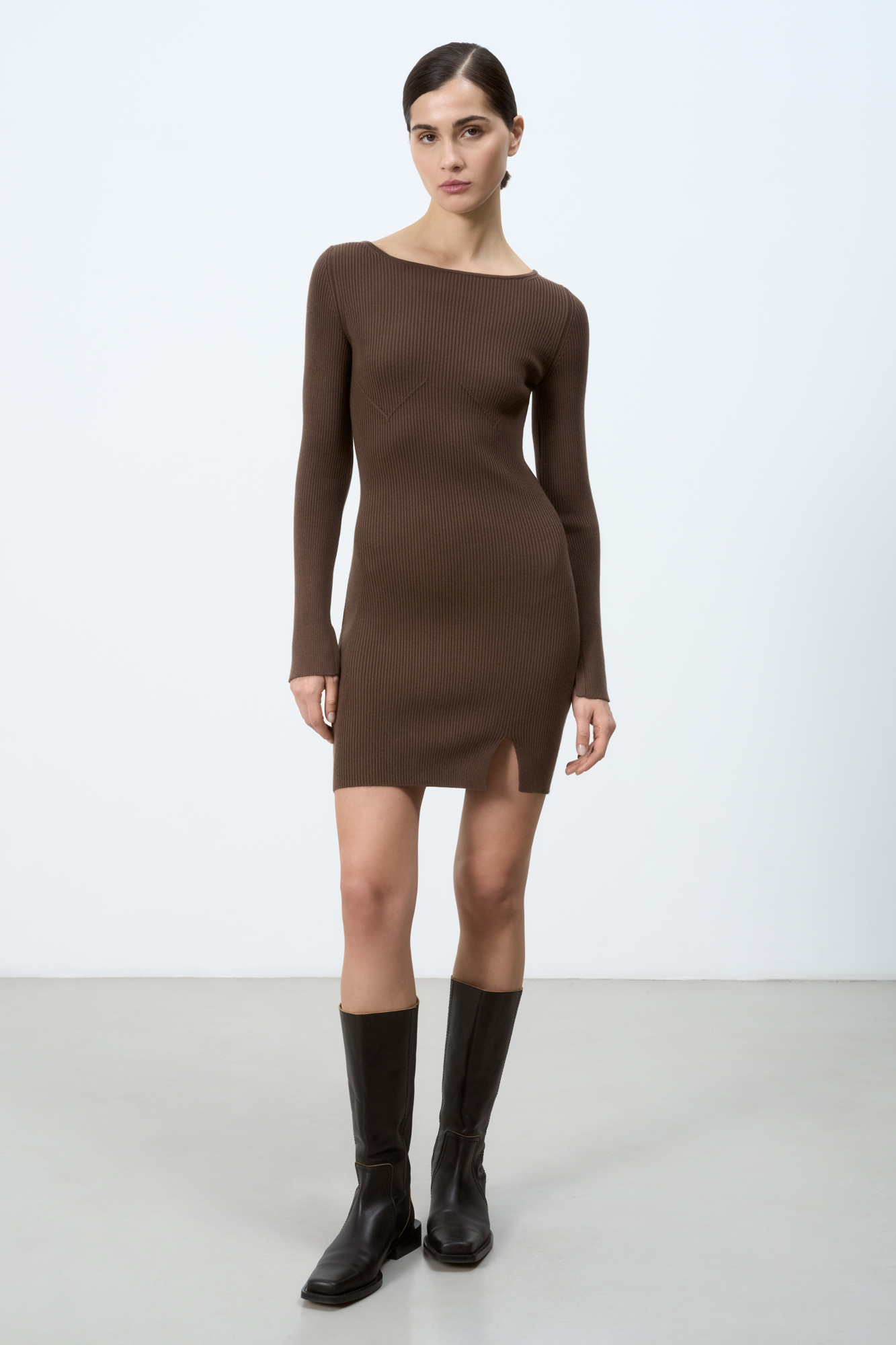 Трикотажное мини платье из шерсти с добавлением вискозы. Модель по фигуре с круглым вырезом горловины, длинными рукавами и невысоким разрезом спереди. Изделие декорировано объемными вытачками, имитирующими бюстье. 