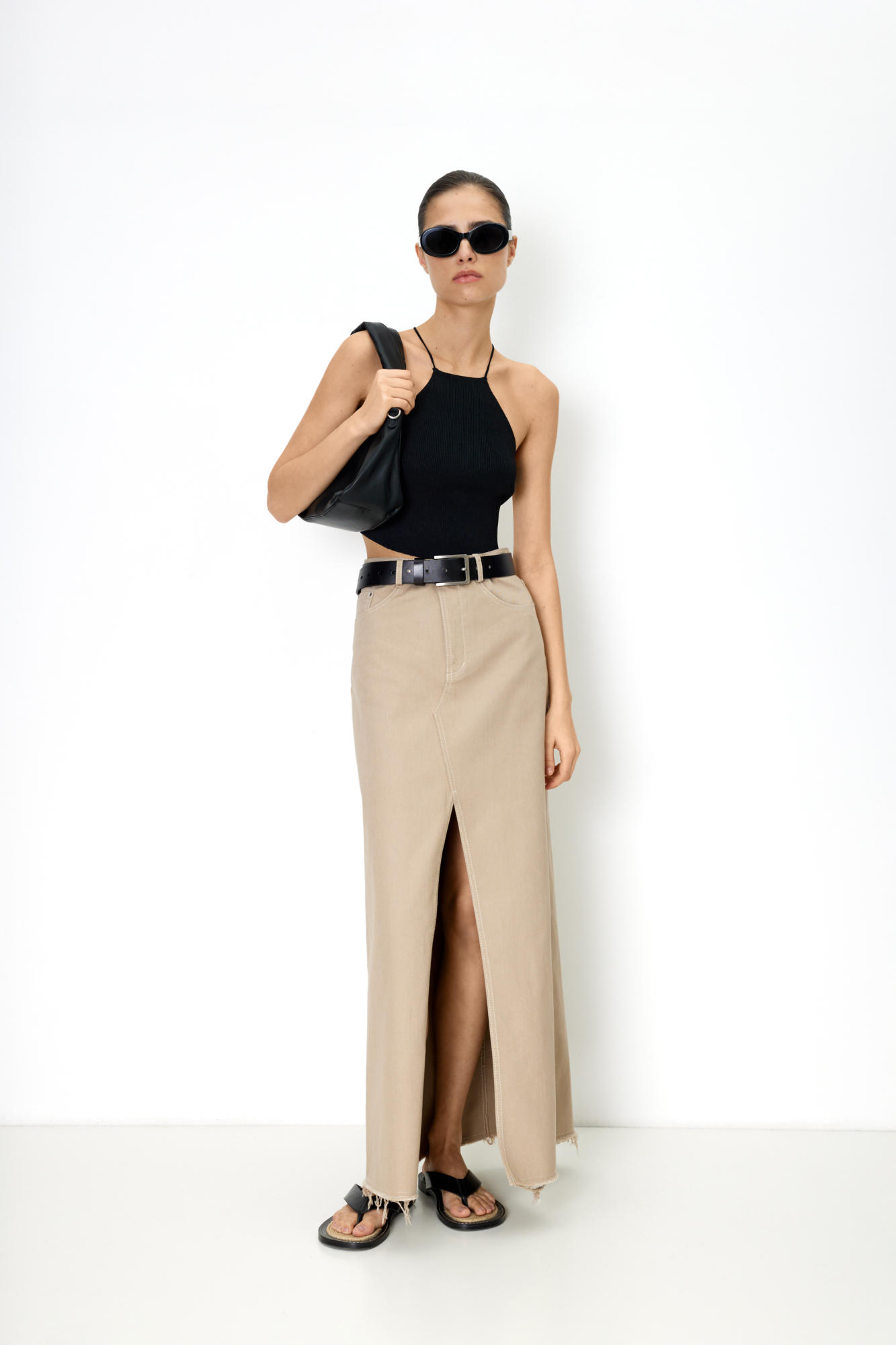 Джинсовая юбка из хлопка. Модель с разрезом спереди и необработанным низом. Шлевки на поясе для ремня, пять карманов, застежка на молнию и пуговицу.