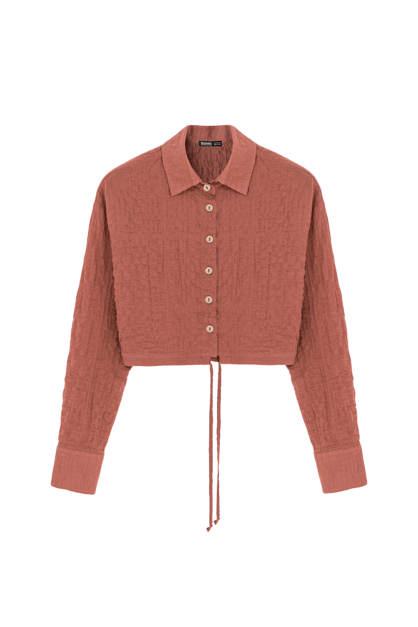 Укороченная рубашка из текстурной марлевки. Модель прямого кроя, с длинными рукавами, классическим отложным воротником, кулиской по низу и застежкой на пуговицы.