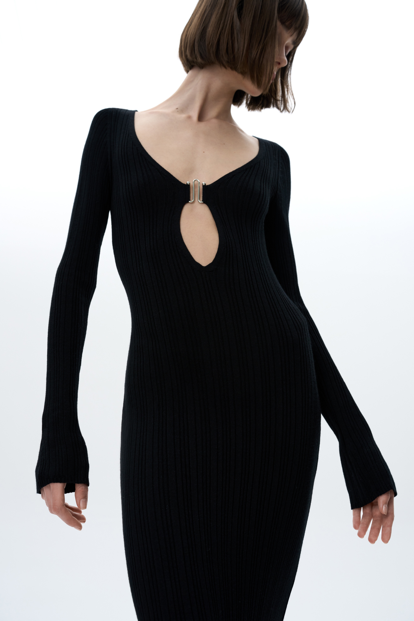 Трикотажное платье длины миди из тонкой вискозы. Модель приталенного силуэта, с длинным рукавом и глубоким вырезом декольте, декорированным металлической перемычкой. 