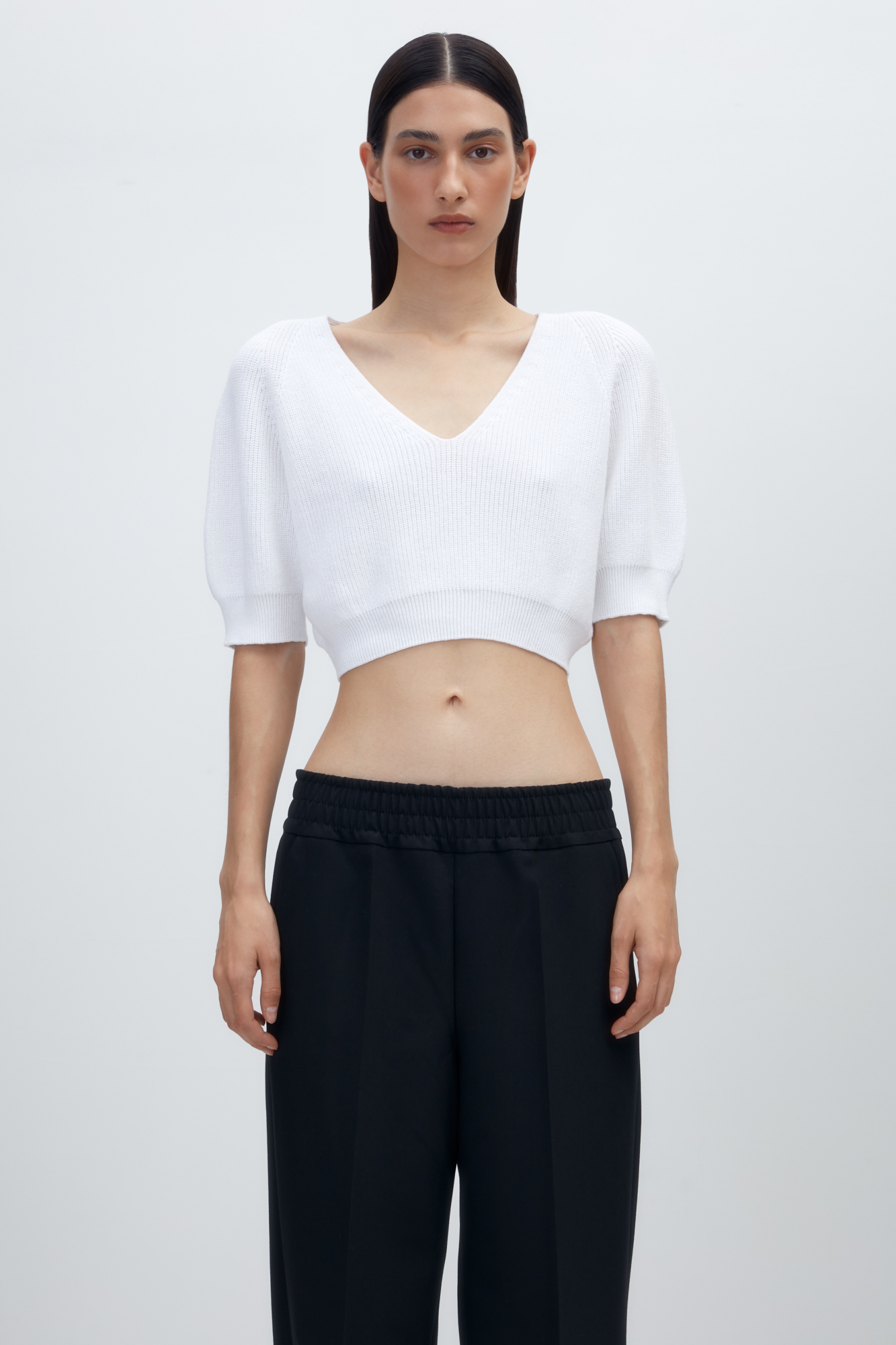 Трикотажный топ из хлопка с V-образным вырезом и коротким рукавом. Манжеты и низ изделия в рубчик.