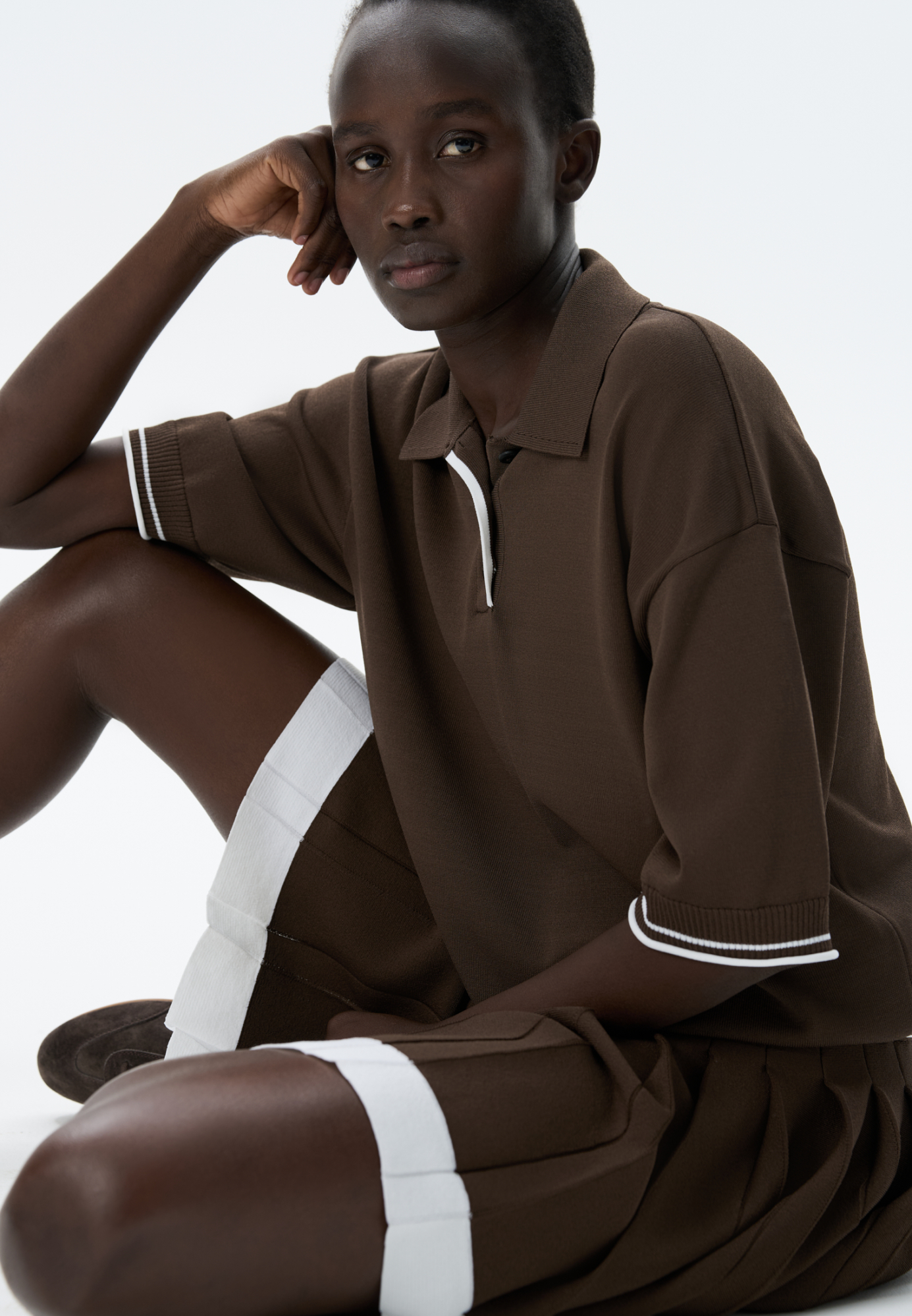 Трикотажная футболка поло из вискозы. Модель прямого силуэта, со спущенной линией плеч, короткими рукавами, отложным воротником-поло и планкой с тремя пуговицами. Рукава и нижний край изделия декорированы кантом контрастного цвета. 