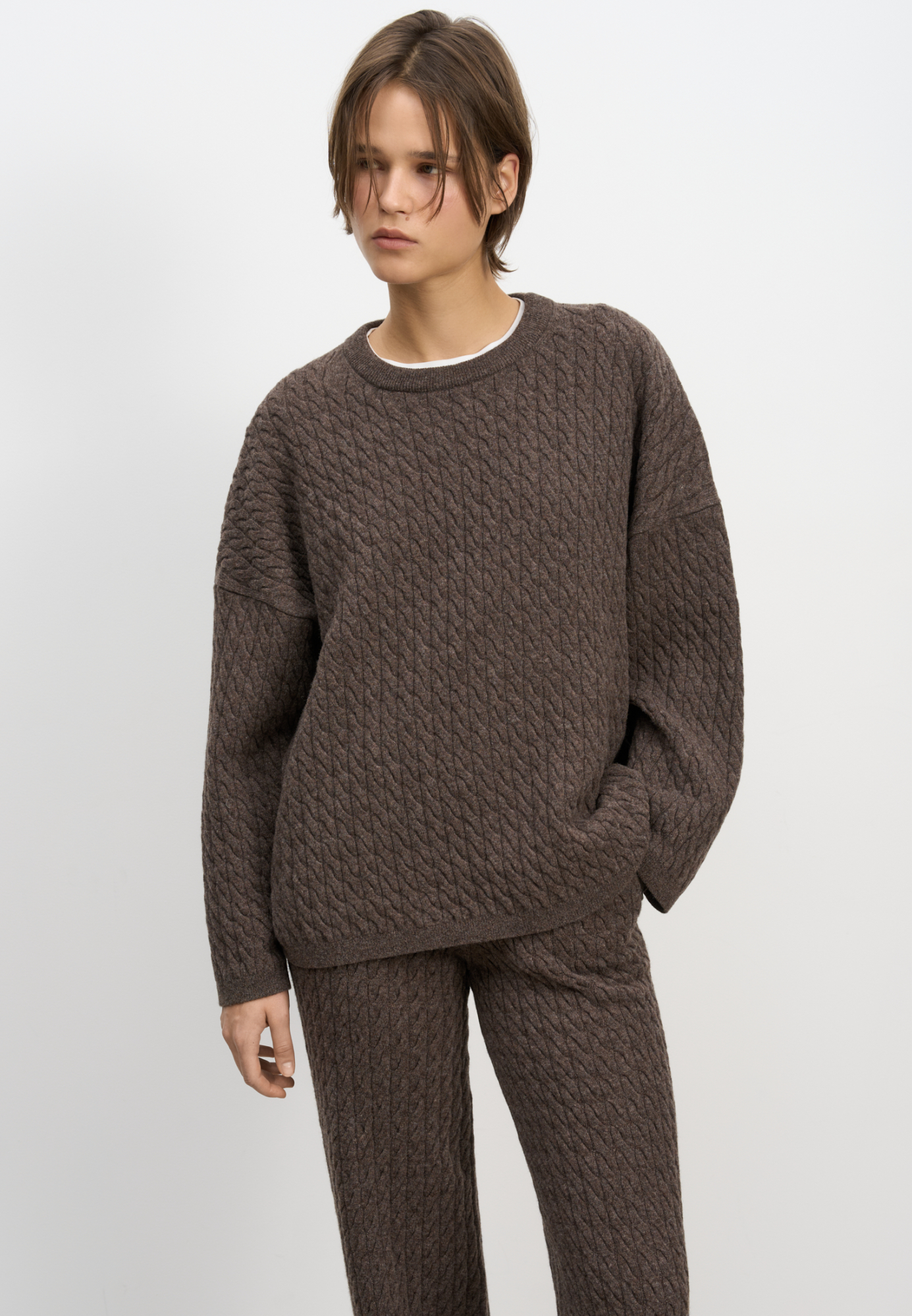 Трикотажный джемпер с объемными косами из 100% шерсти мериноса экстрафайн. Модель свободного силуэта, со спущенной линией плеч и круглым вырезом горловины, оформленным двойной бейкой. Края изделия выполнены в мелкий рубчик.