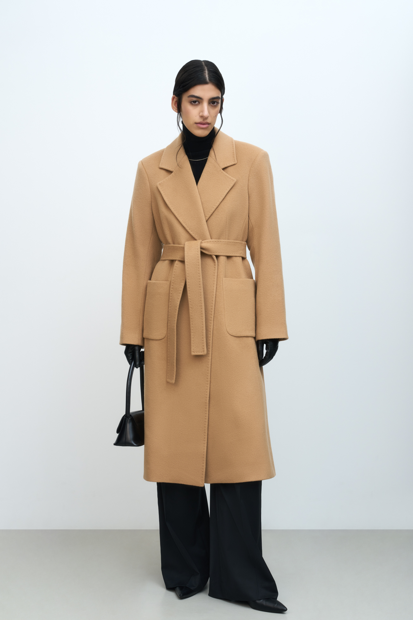 Классическое шерстяное пальто с поясом из основной ткани. Модель приталенного силуэта. Отложной воротник с прямоугольными лацканами и накладные карманы.