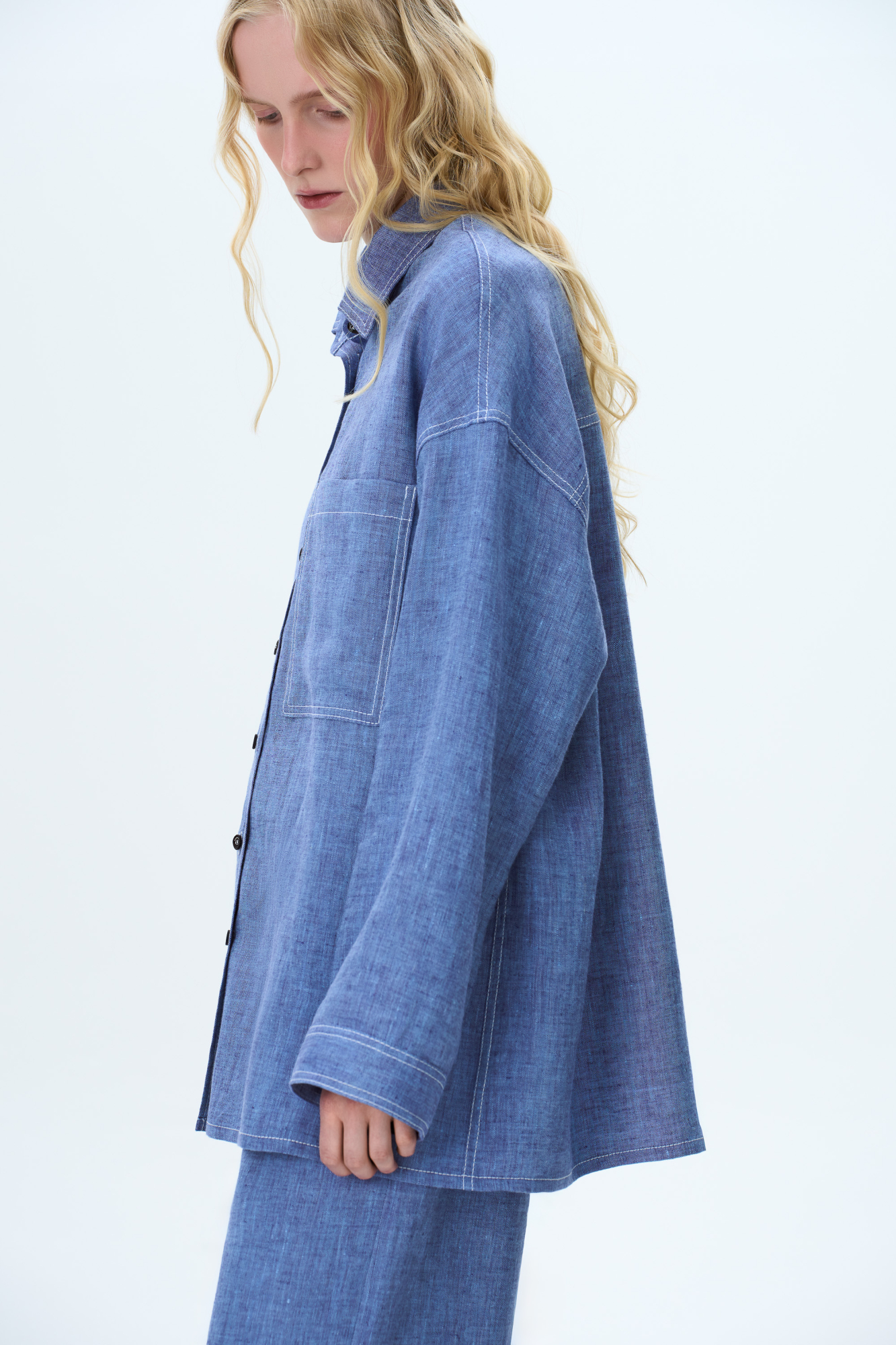 Льняная рубашка с накладным карманом на груди. Модель свободного силуэта с классическим отложным воротником, спущенной линией плеч и большим нагрудным карманом. Застежка на пуговицы. Изделие декорировано брендированным ярлыком на рукаве и пуговицами на манжетах рукавов.