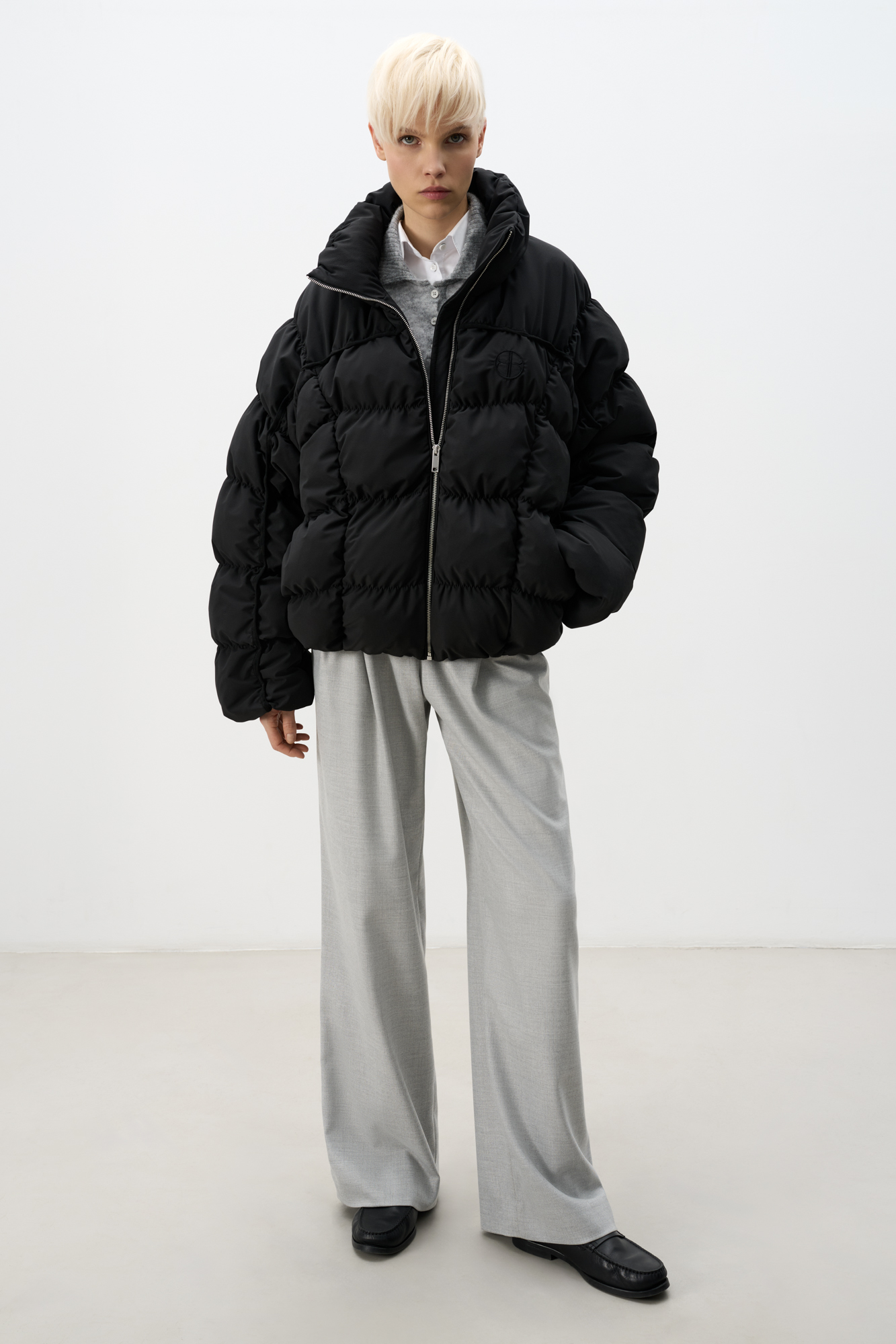 Стеганый пуховик с воротником-стойкой. Застежка на молнию. Низ изделия выполнен на регулируемой кулиске. Вышитый логотип на груди. На подкладке. 