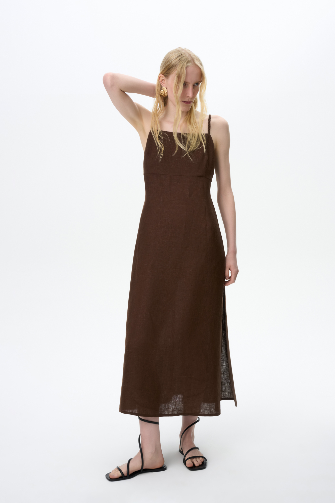 Сарафан длины миди из 100% льна. Модель приталенного силуэта, на тонких бретельках в виде косичек и высоким разрезом сбоку. Спинка изделия выполнена на резинке. 