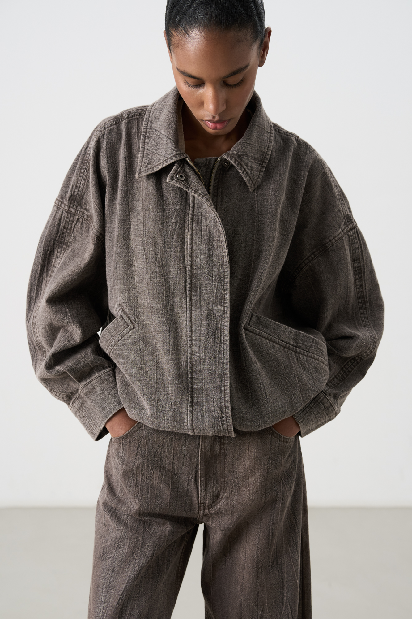 Куртка из плотного льна. Модель свободного кроя, с классическим отложным воротником, застежкой на молнию и кнопки под планкой. Низ изделия выполнен на регулируемой кулиске. 