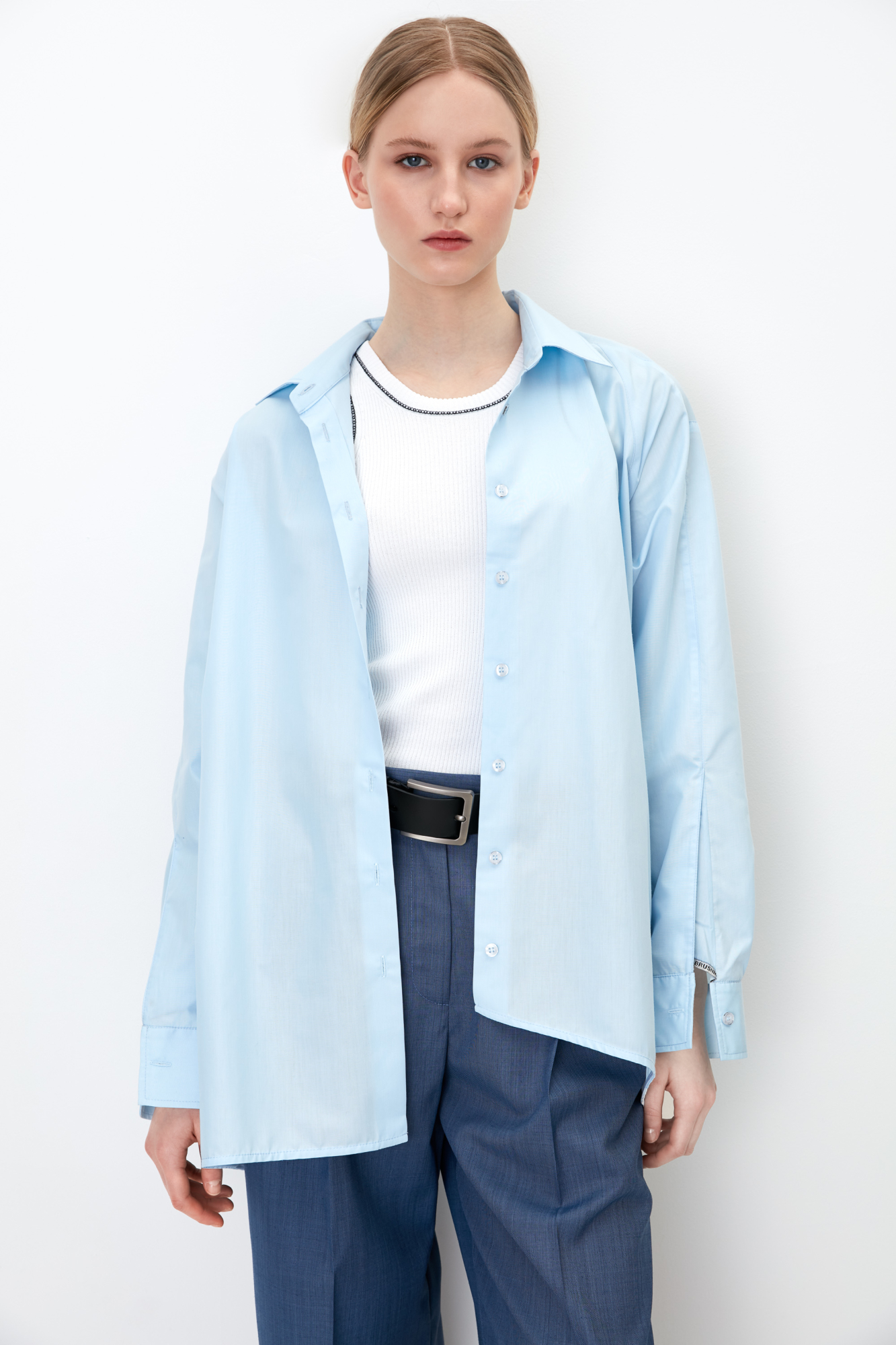 Рубашка на пуговицах с расклешенными рукавами, регулируемым манжетом и асимметричным краем.