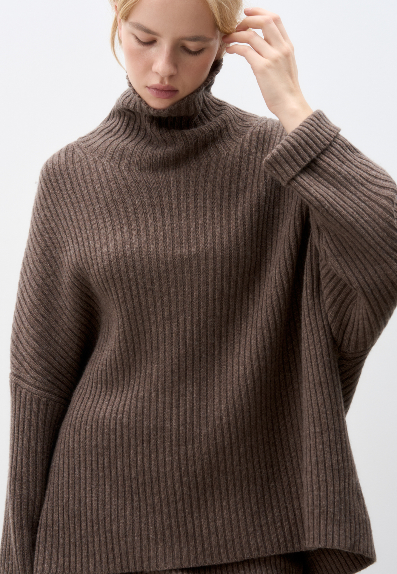 Широкий трикотажный джемпер из шерсти с добавлением кашемира. Модель свободного силуэта, со спущенной линией плеча, отворотами на манжетах и высоким свободным воротником.