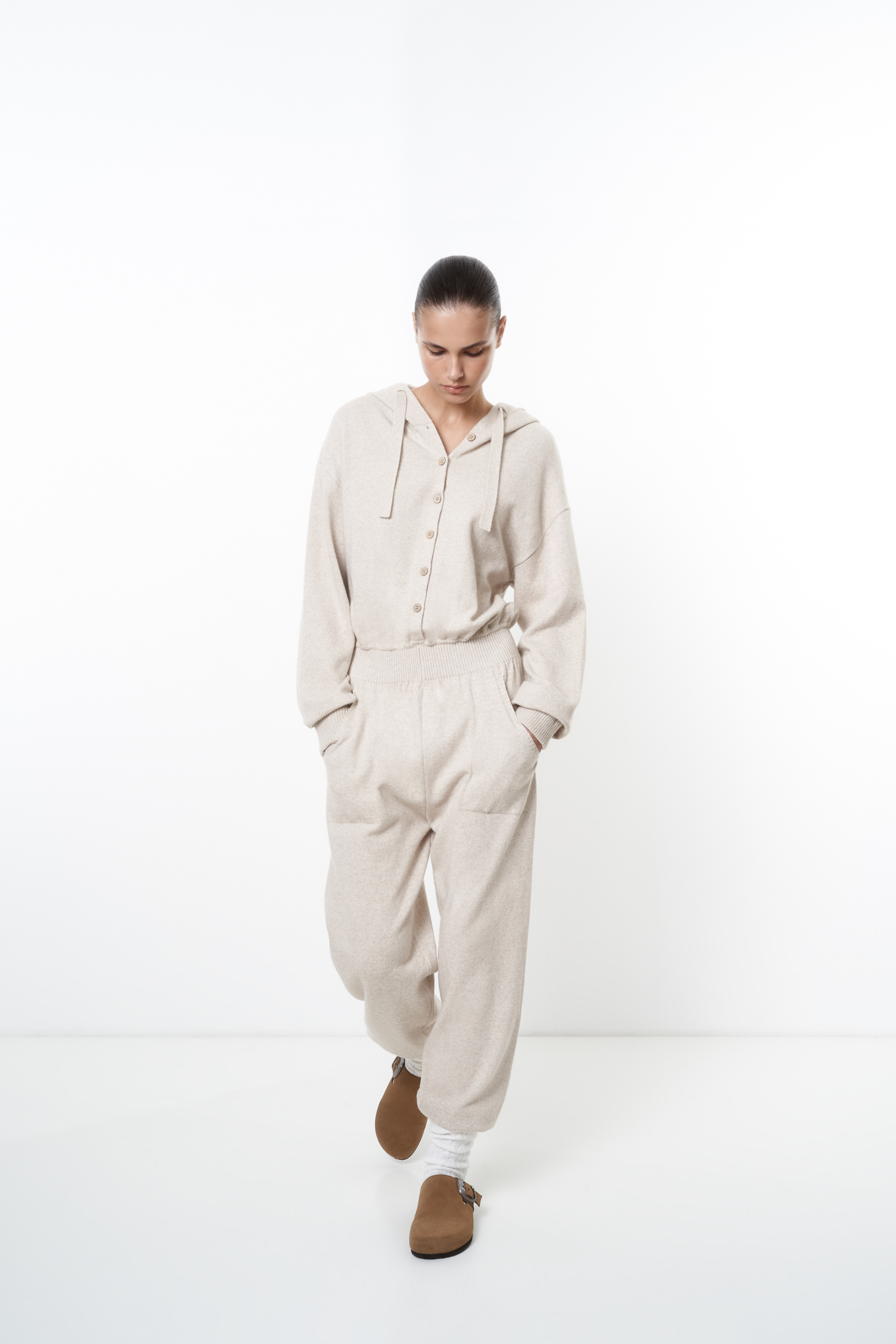 Трикотажный комбинезон из шерсти и кашемира, состоящий из худи и брюк. Худи с капюшоном и застежкой на пуговицы, брюки с широким эластичным поясом, боковыми карманами и манжетами на резинке.