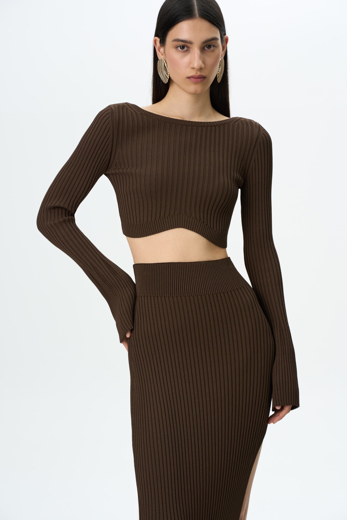 Укороченный трикотажный топ из вискозы в рубчик. Обтягивающая модель с открытой спиной. Дополнить образ можно юбкой в таком же стиле.