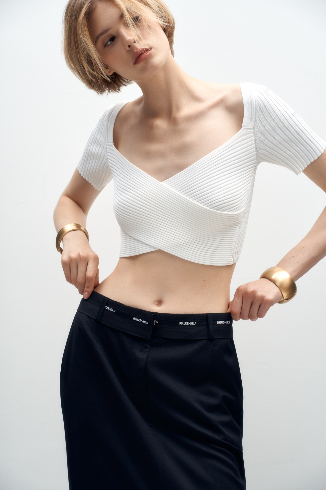 Короткий трикотажный топ из вискозы. Модель приталенного силуэта, с коротким рукавом, глубоким вырезом и скрещенным лифом. Изделие выполнено в рубчик.