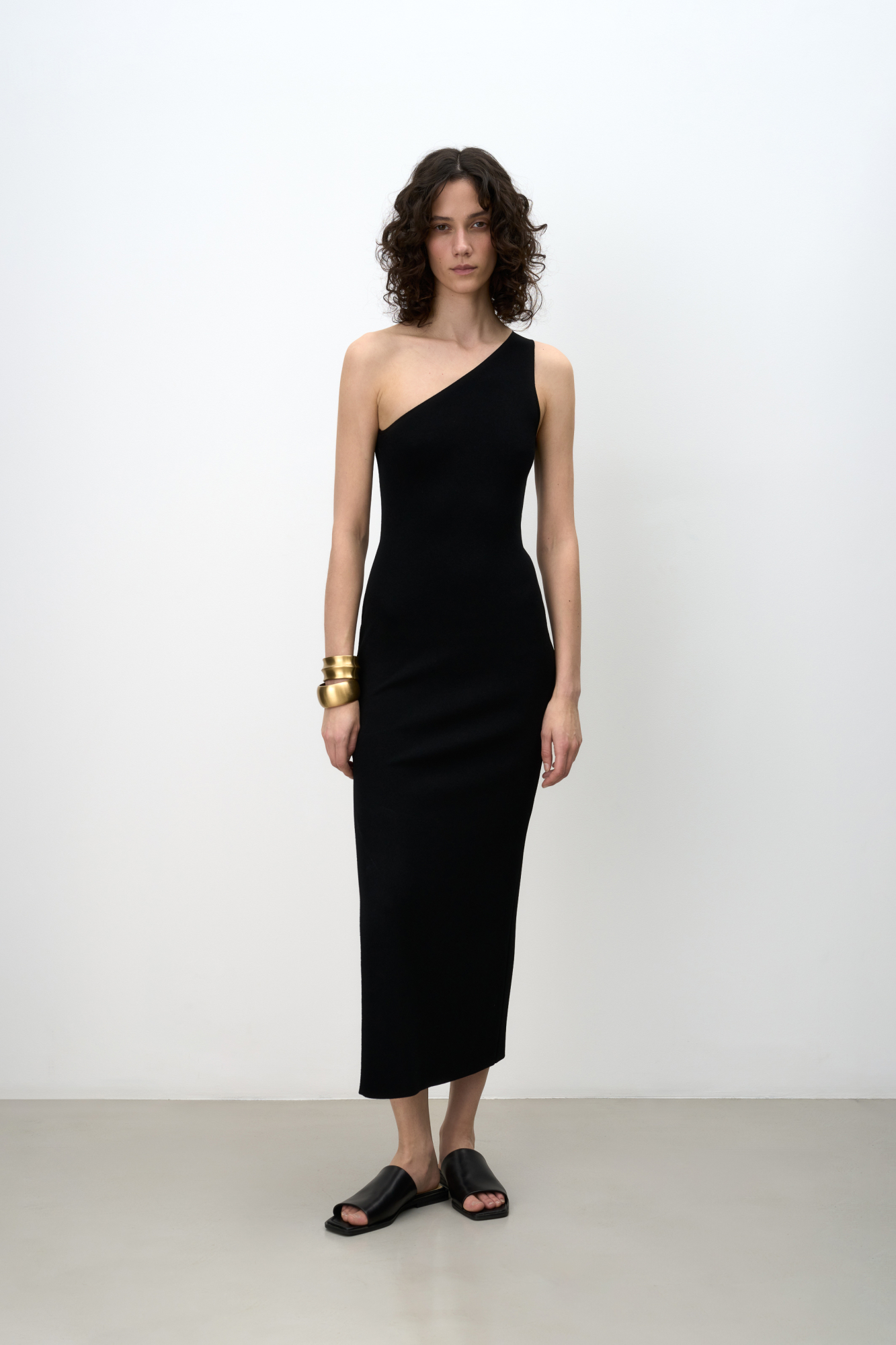 Трикотажное платье из вискозы длины миди. Модель приталенного силуэта, без рукавов, с широкой лямкой на одно плечо и разрезом сбоку.