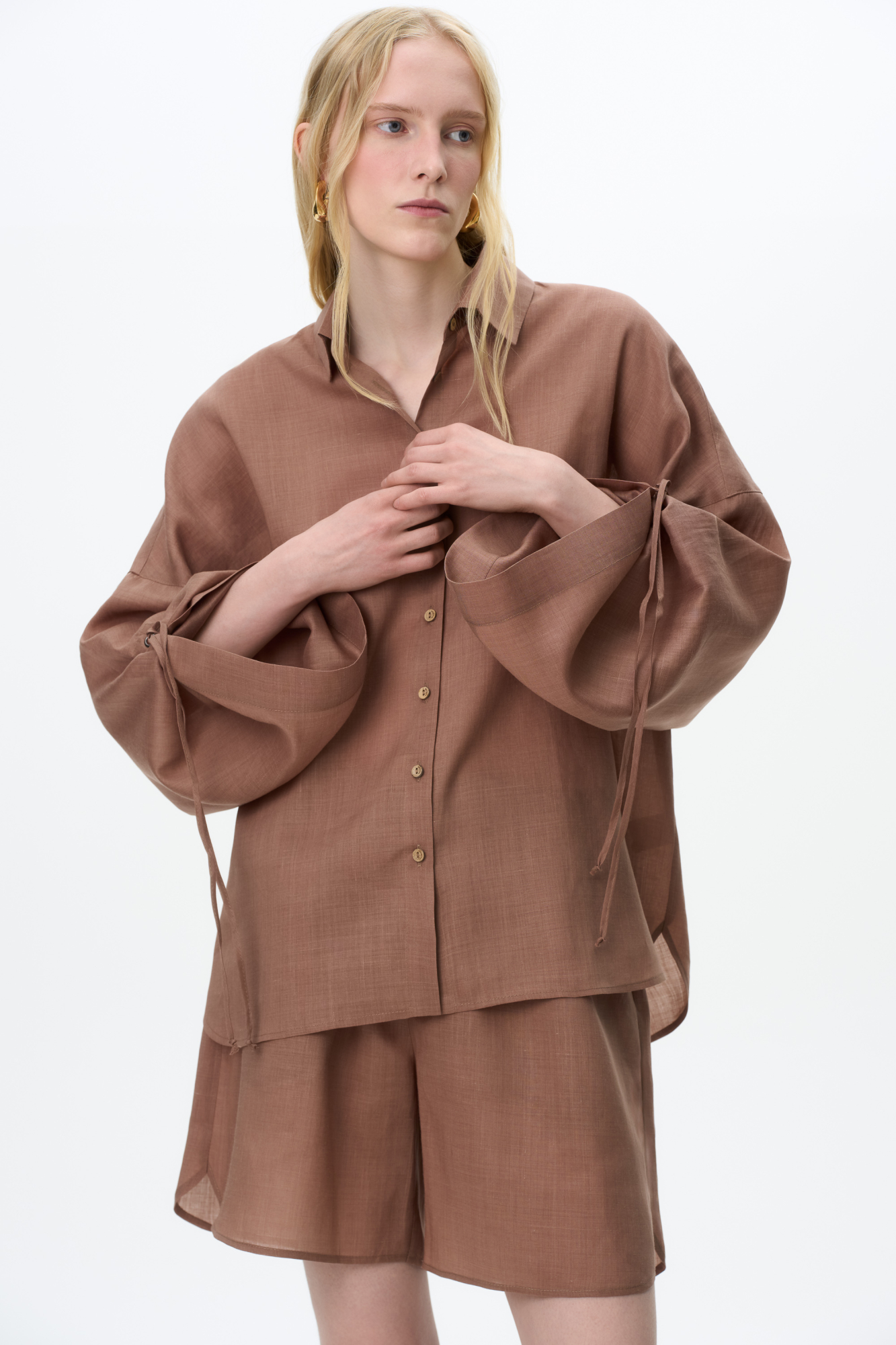 Комплект из 100% крапивы, состоящий из рубашки и шорт. Рубашка с длинными расклешенными рукавами на кулиске, классическим отложным воротником и застежкой на пуговицы. Короткие шорты с боковыми карманами и эластичным поясом на резинке.