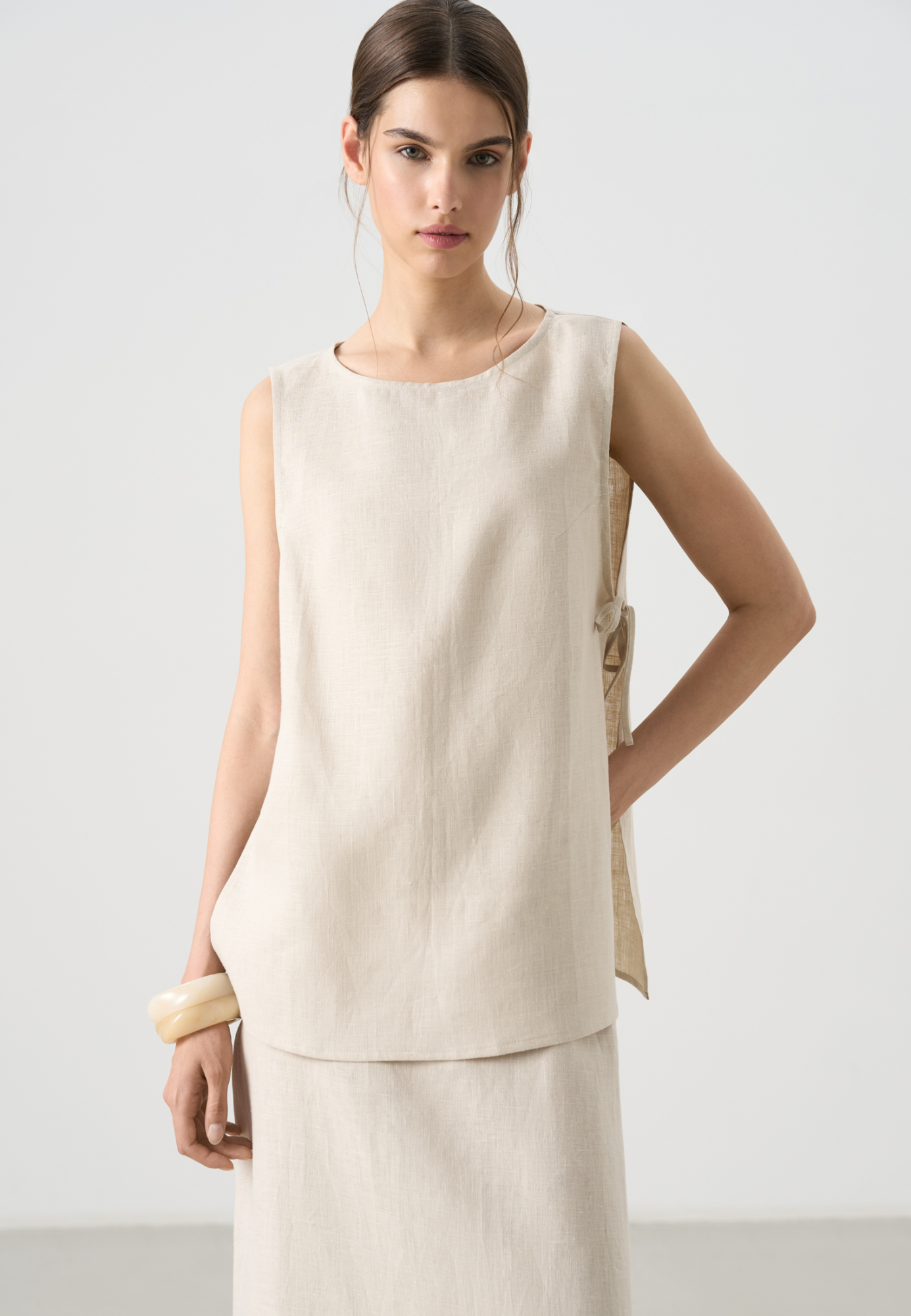 Топ из 100% льна. Модель свободного кроя, без рукавов, с круглым вырезом горловины. Изделие фиксируется завязками по бокам.