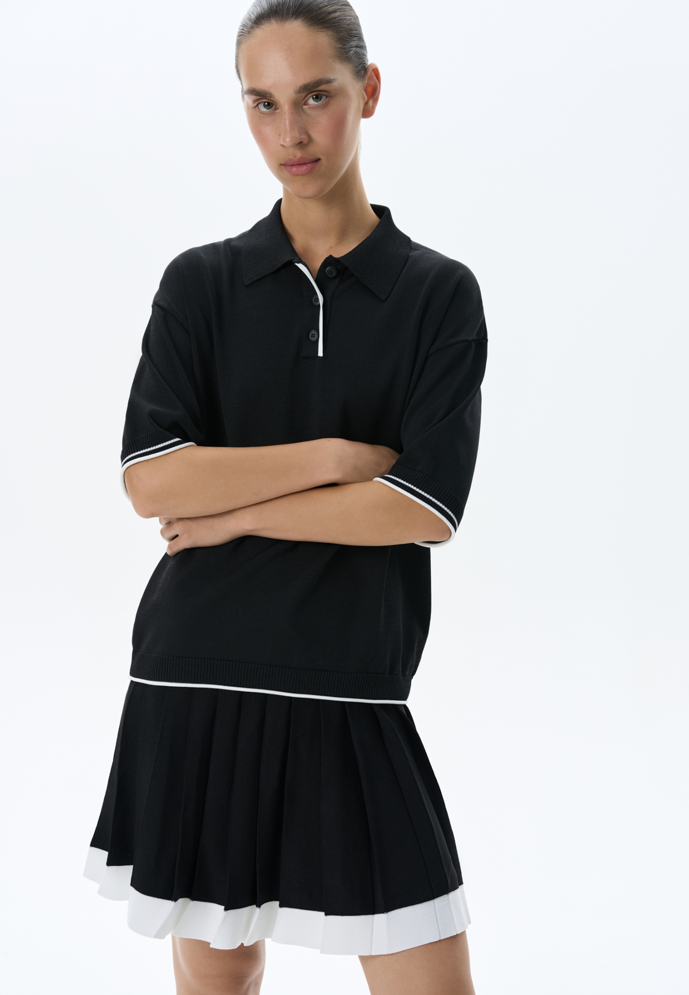 Трикотажная футболка поло из вискозы. Модель прямого силуэта, со спущенной линией плеч, короткими рукавами, отложным воротником-поло и планкой с тремя пуговицами. Рукава и нижний край изделия декорированы кантом контрастного цвета. 