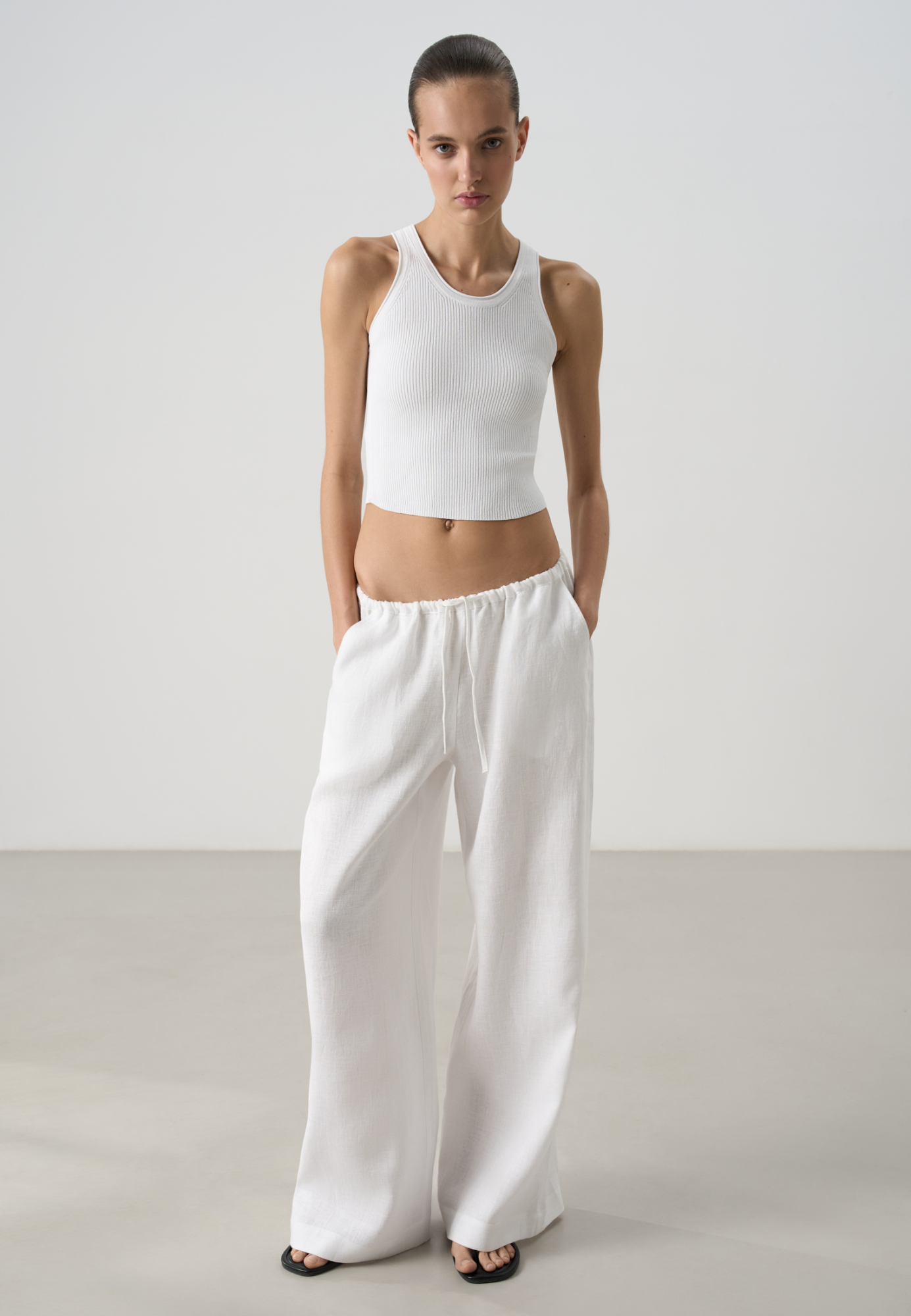 Широкие брюки из 100% льна. Модель свободного прямого кроя с врезными карманами по бокам. Изделие выполнено с поясом на узкой резинке, дополненным кулиской.