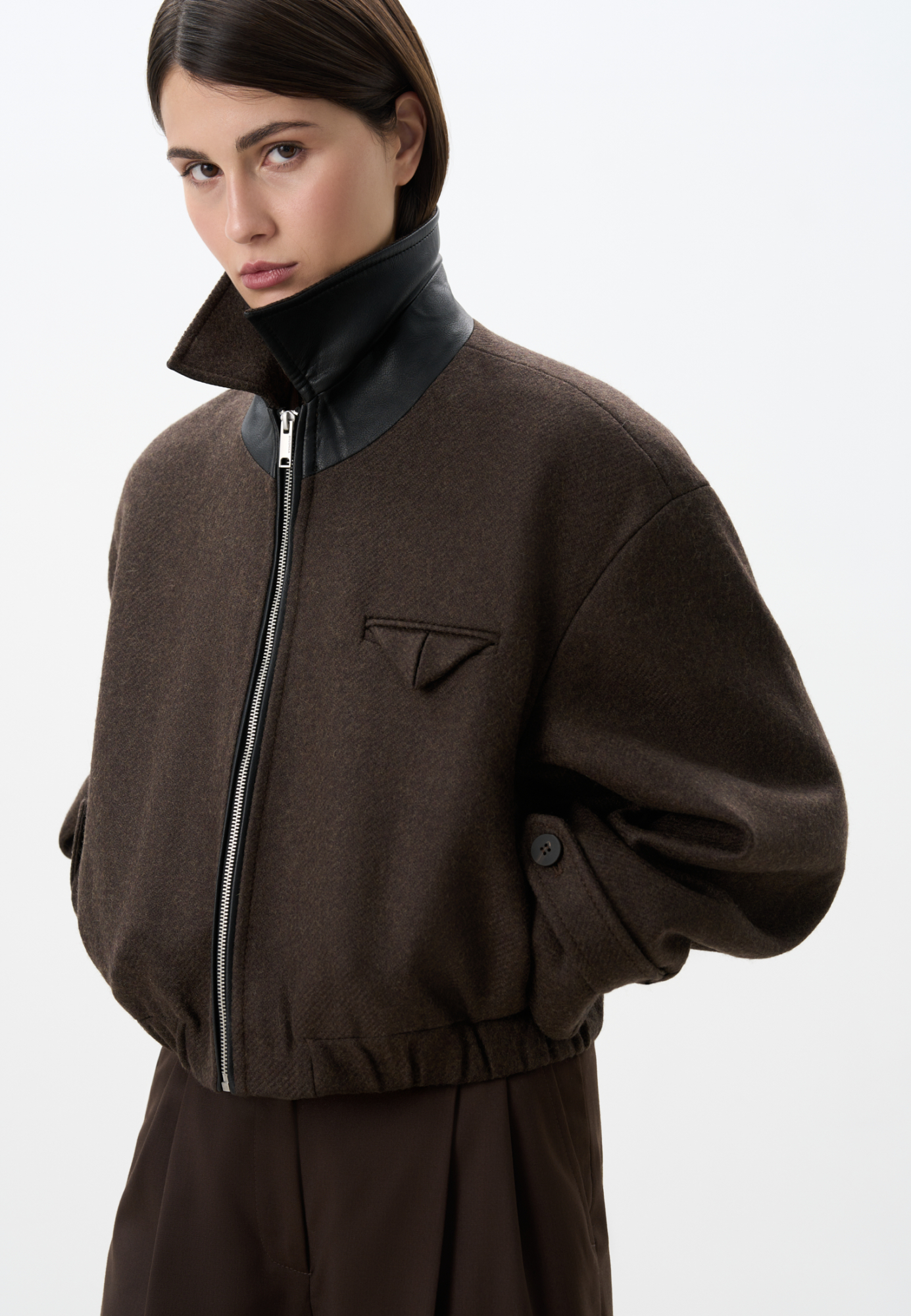 Шерстяной бомбер с отложным с воротником. Модель прямого силуэта с подплечниками и имитацией кармана на груди. Длинные рукава с патами на манжетах. Воротник декорирован вставкой из экокожи. Застежка на молнию. Изделие на подкладке.