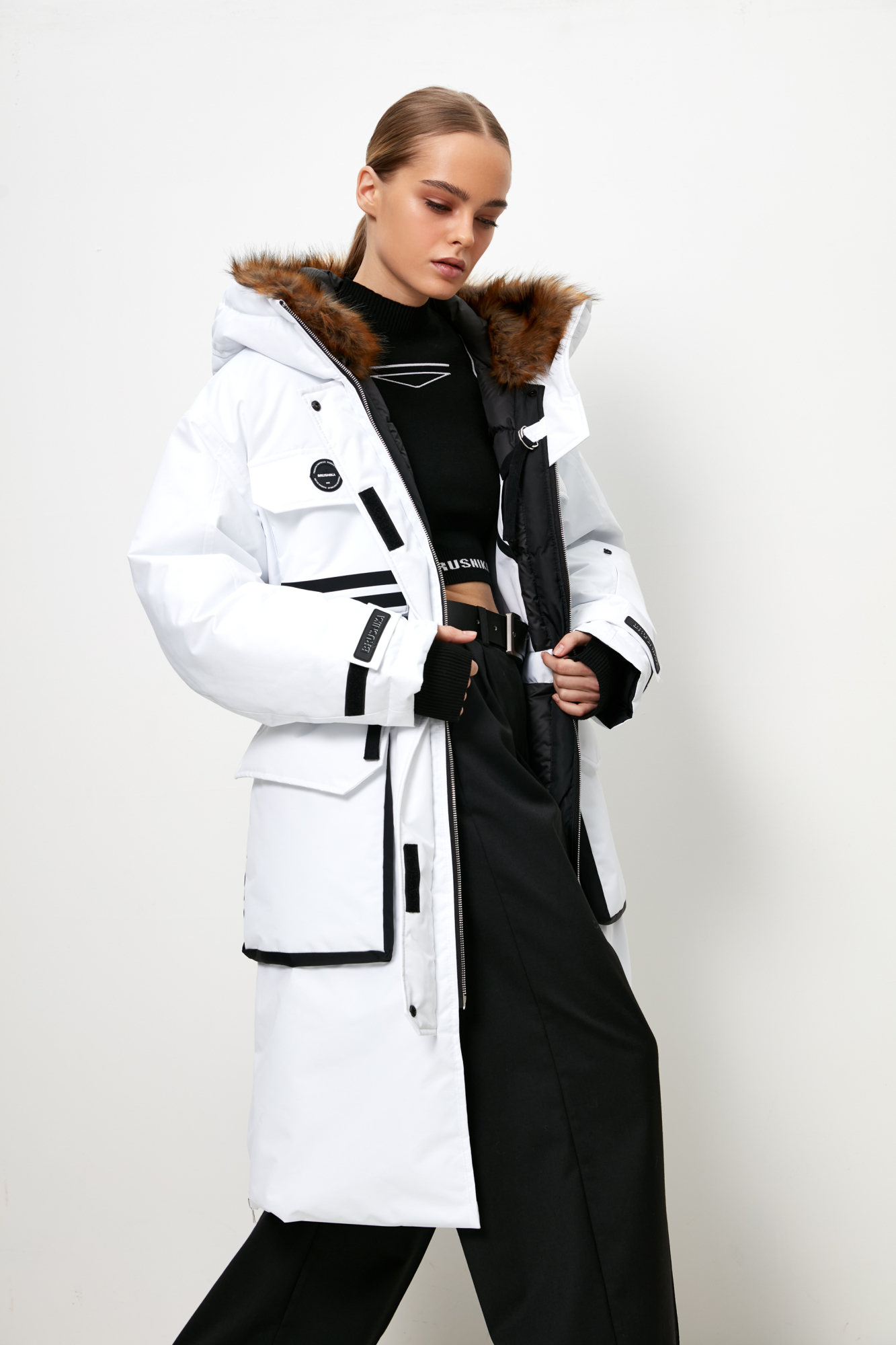 Удлиненная куртка на молнии с капюшоном из экомеха, наполнитель пух-перо, внутренняя кулиска на талии, накладные карманы спереди, фиксаторами на манжетах. Хороший показатель водонепроницаемости, выдержит слабый дождь и мокрый снег.