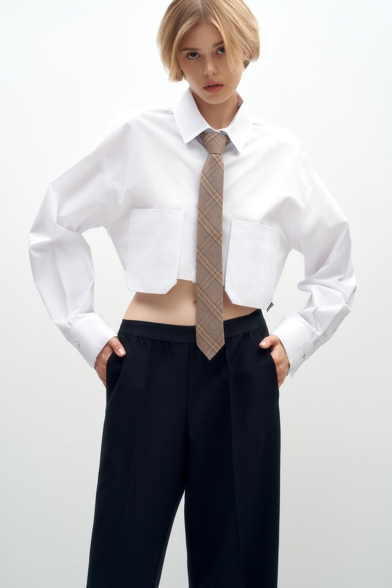 Рубашка из хлопка с добавлением полиэстера. Модель укороченного силуэта, с классическим отложным воротником, длинными рукавами и двумя накладными карманами на груди. Застежка на пуговицы. Имитация необработанного края.