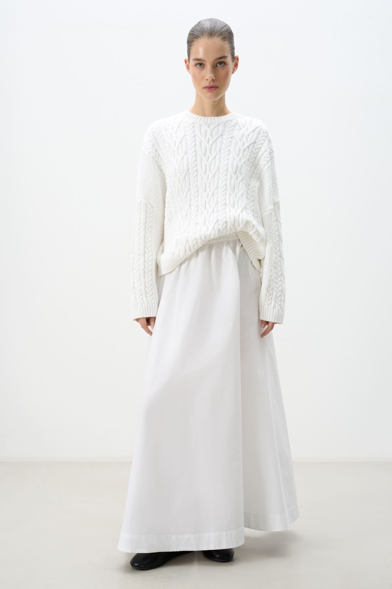 Трикотажный джемпер из вискозы и хлопка. Модель свободного силуэта со спущенной линией плеч, объемными рукавами и круглым вырезом горловины. Изделие декорировано фактурной вязкой в виде кос разной толщины. Края выполнены в рубчик. 