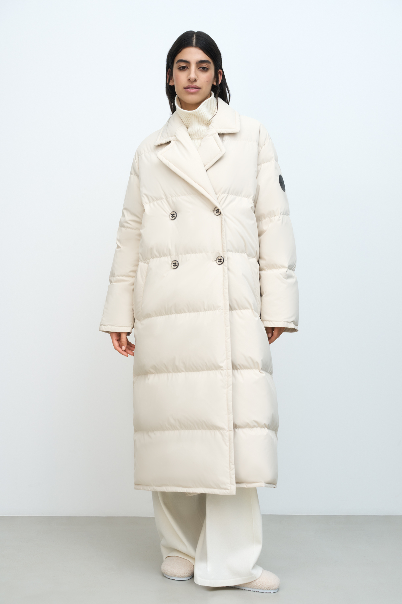 Длинный пуховик на пуговицах. Модель с поясной сумкой. Средний показатель водонепроницаемости, наполнитель пух-перо.