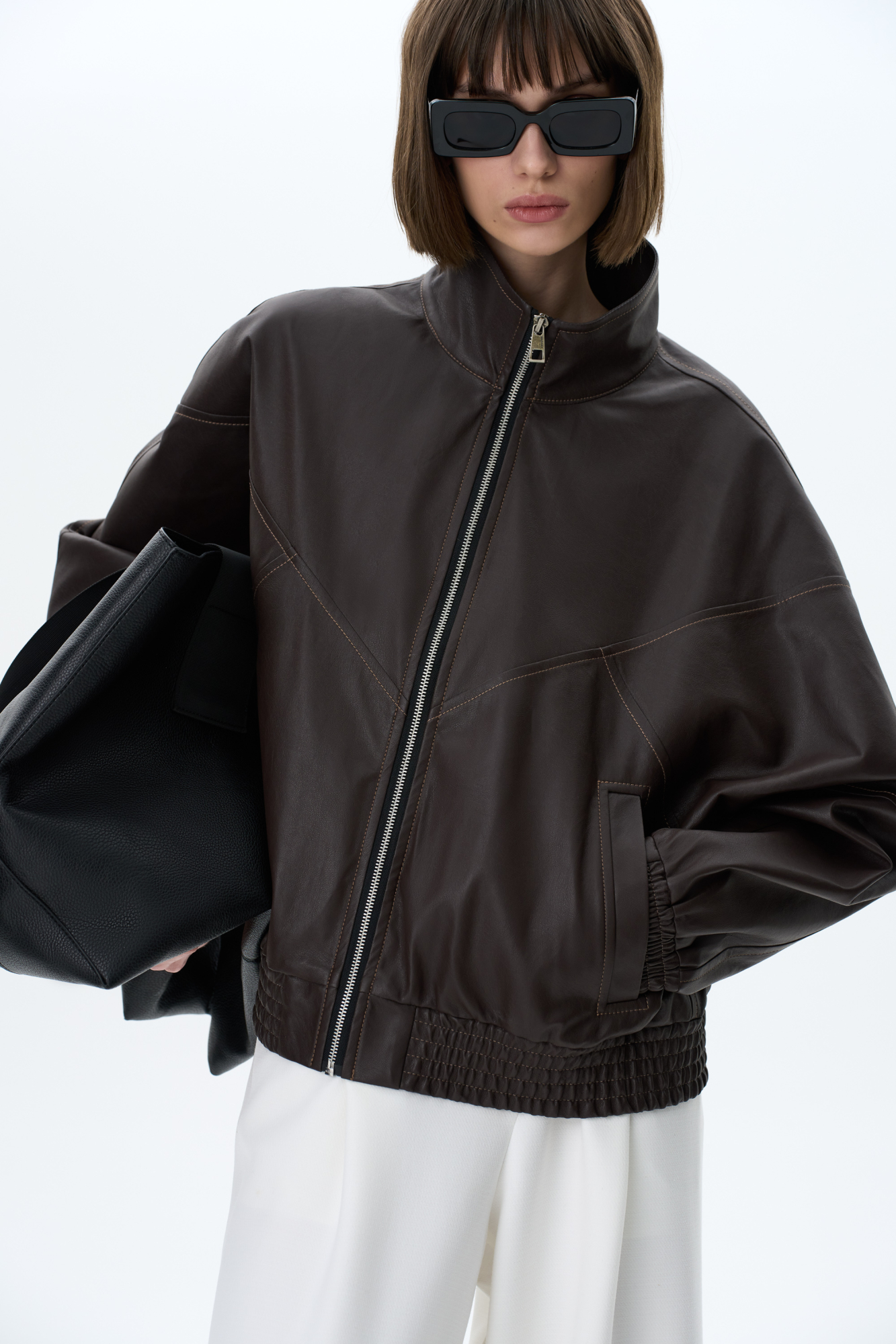 Бомбер из экокожи с боковыми карманами. Модель свободного силуэта с воротоником стойкой. Низ изделия и манжеты рукавов выполнены на резинке. Брендированный ярлык на спине. Застежка на молнию. Без подкладки.