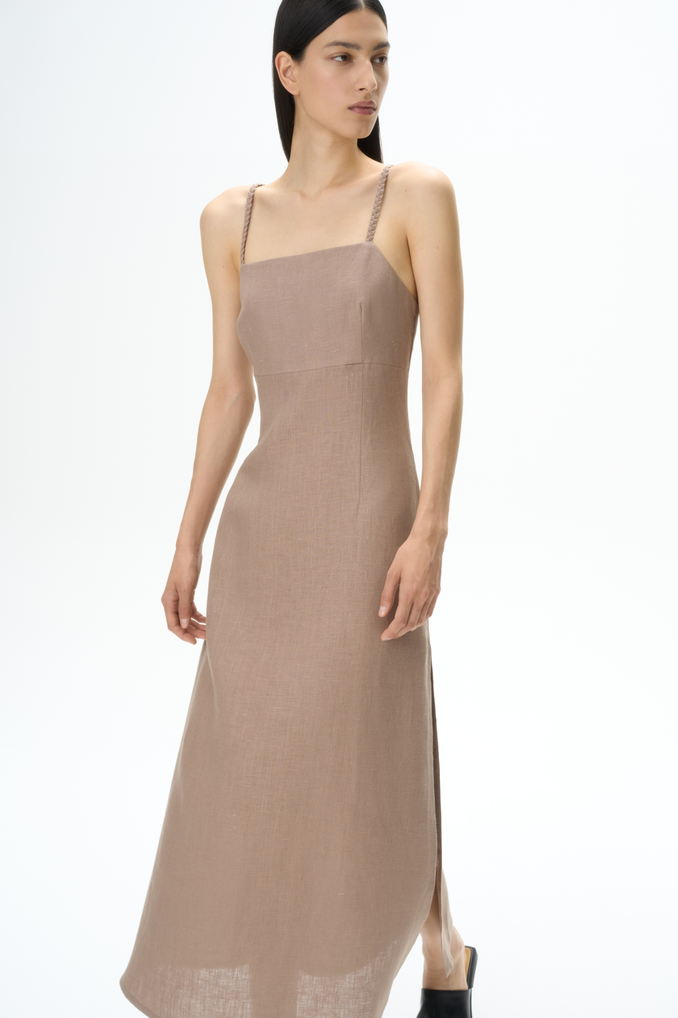 Сарафан длины миди из 100% льна. Модель приталенного силуэта, на тонких бретельках в виде косичек и высоким разрезом сбоку. Спинка изделия выполнена на резинке.
