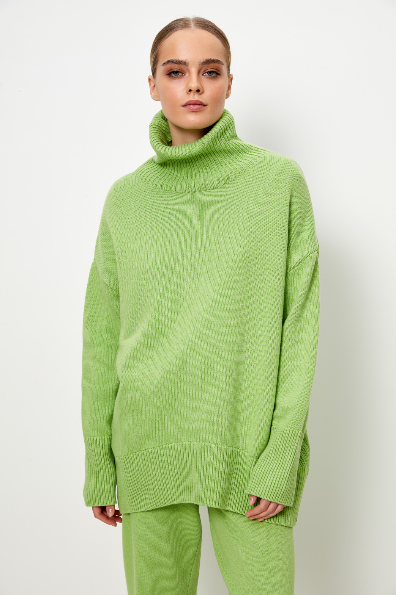 Трикотажный джемпер из мягкой шерсти с добавлением кашемира. Высокий ворот, заниженная линия плеч, удлиненная спинка. Края изделия сделаны в широкий рубчик. Можно дополнить комплектными брюками.