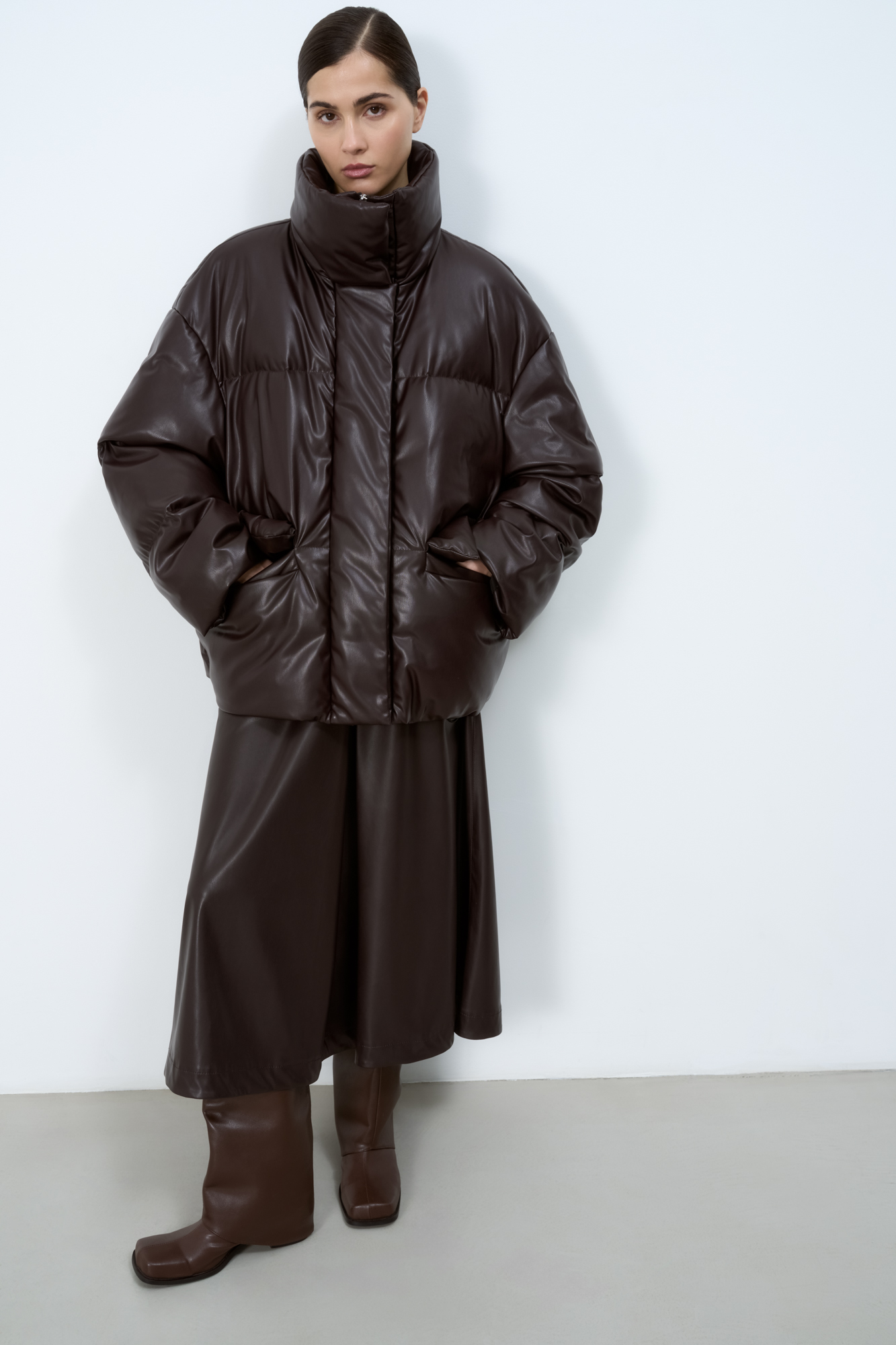 Утепленный пуховик из экокожи. Модель свободного силуэта с боковыми карманами и воротником-стойкой. Застежка на потайную молнию и магнитные пуговицы. На подкладке.
