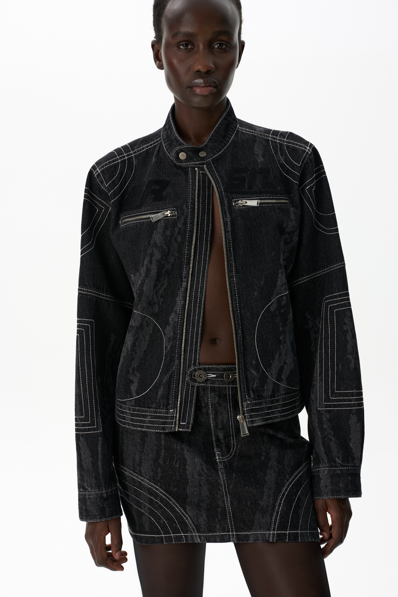 Джинсовая юбка длины мини. Изделие декорировано отстрочкой контрастного цвета, формирующей графические акценты. Застежка на молнию и пуговицу. Без подкладки.