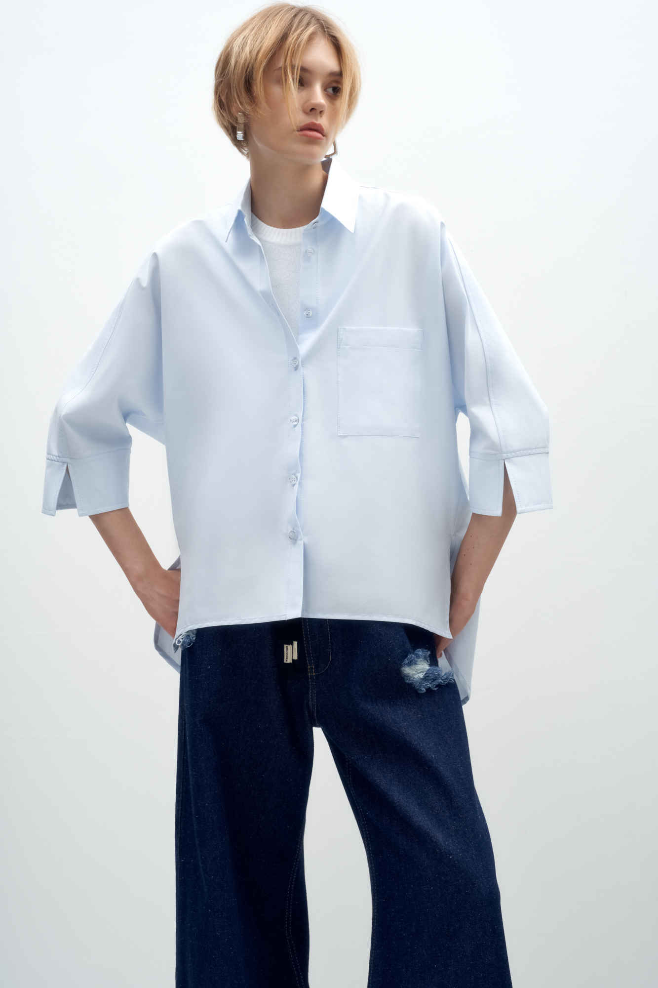 Классическая рубашка из хлопка. Модель свободного кроя, с классическим отложным воротником, широким рукавом длины 3/4, накладным карманом на груди и разрезами по бокам. Застежка на пуговицы.