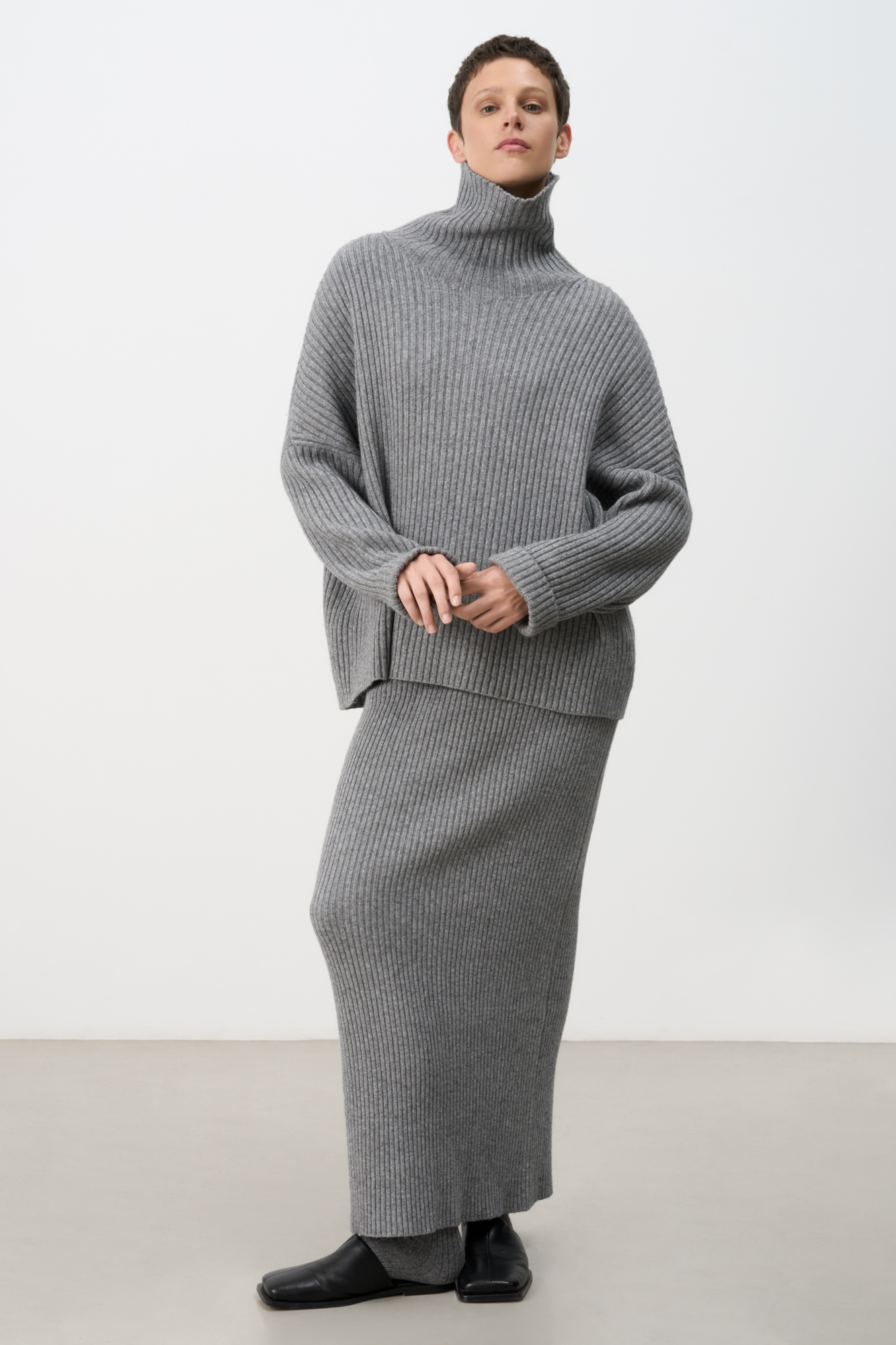 Трикотажная юбка длины макси из кашемира и шерсти. Модель приталенного силуэта, с разрезом сзади и эластичным поясом. Изделие выполнено в рубчик.