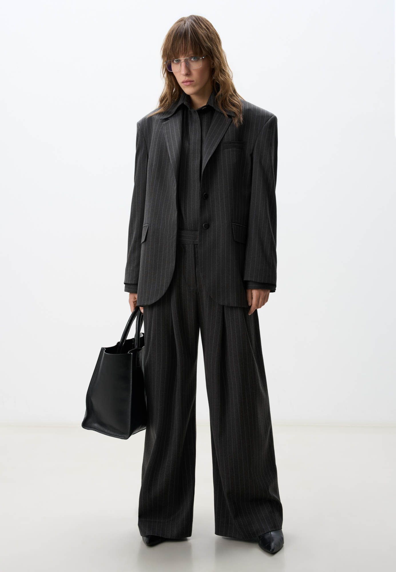 Широкие офисные брюки из шерсти. Модель свободного кроя с защипами спереди, карманами, шлевками на поясе для ремня и застежкой на молнию и скрытую пуговицу.