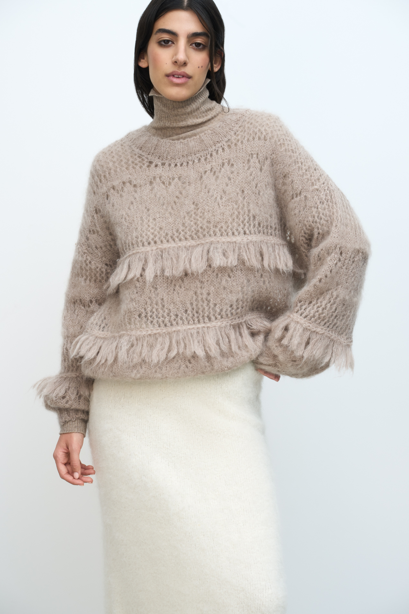 Ажурный джемпер с вывязанным узором и бахромой. Модель свободного силуэта со спущенной линией плеч и круглым вырезом горловины. Края изделия выполнены в рубчик. 