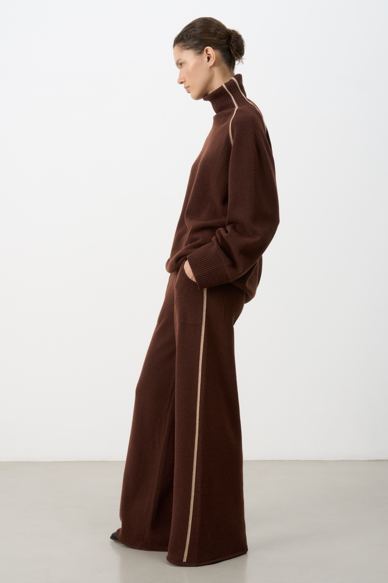 Трикотажные брюки из кашемира и шерсти. Модель свободного силуэта со средней посадкой, боковыми вывязанными карманами и эластичным поясом на кулиске. Изделие декорировано лампасами контрастного цвета.