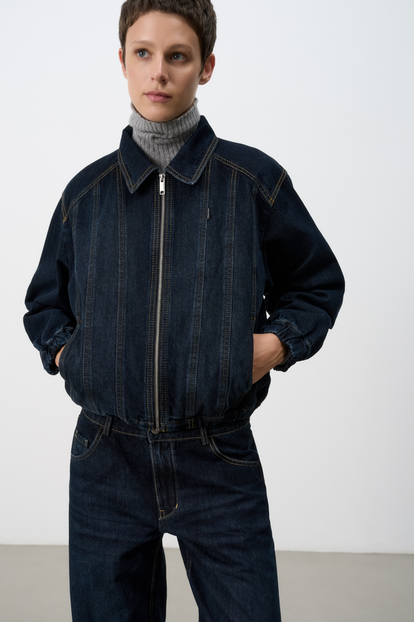 Джинсовый бомбер с манжетами на резинке. Модель свободного силуэта со спущенной линией плеча. Потайные боковые карманы, застежка на молнию.