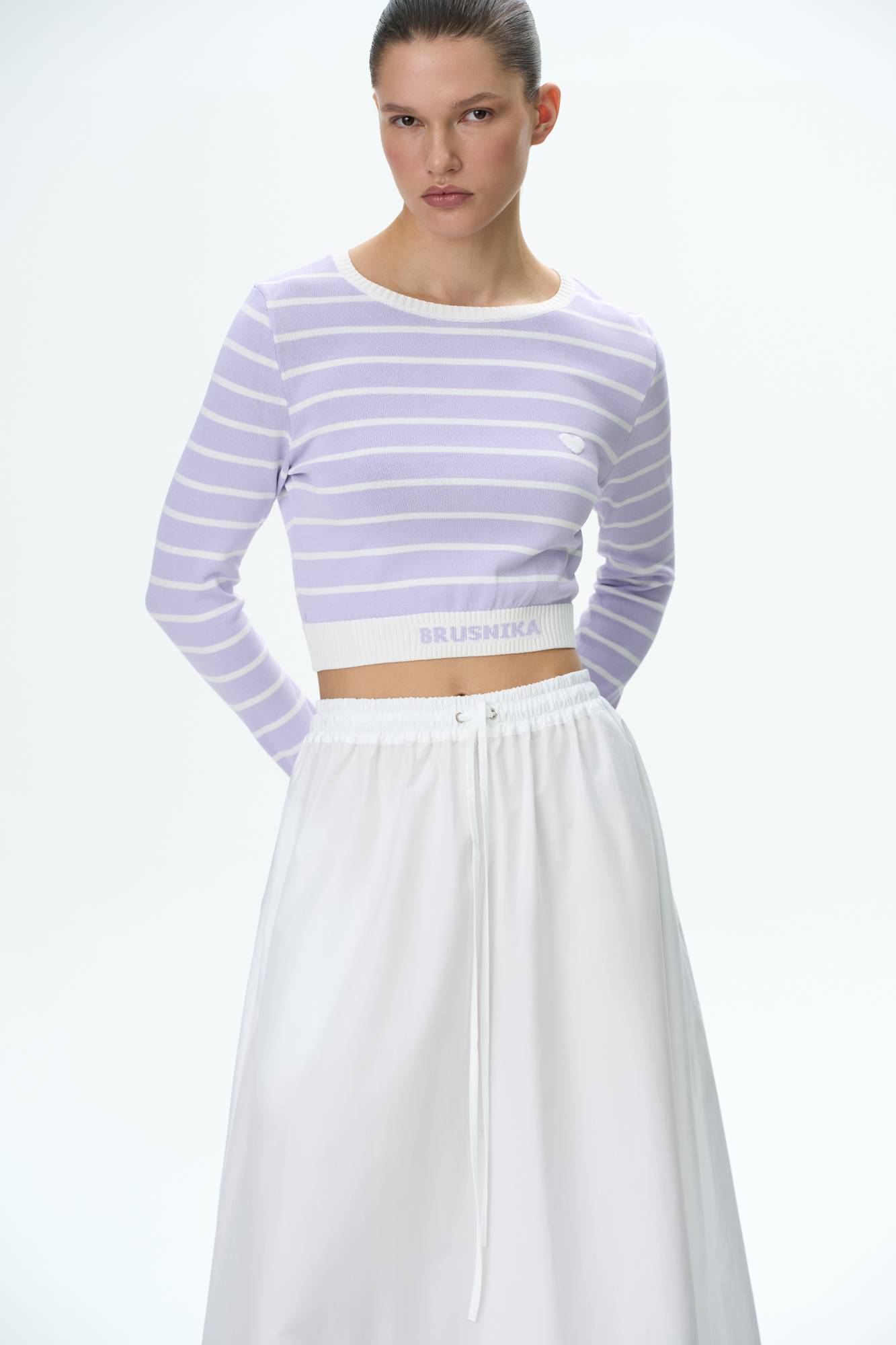 Трикотажный топ в полоску. Круглый вырез, длинные рукава с манжетами. Низ изделия выполнен резинкой с брендированной надписью.