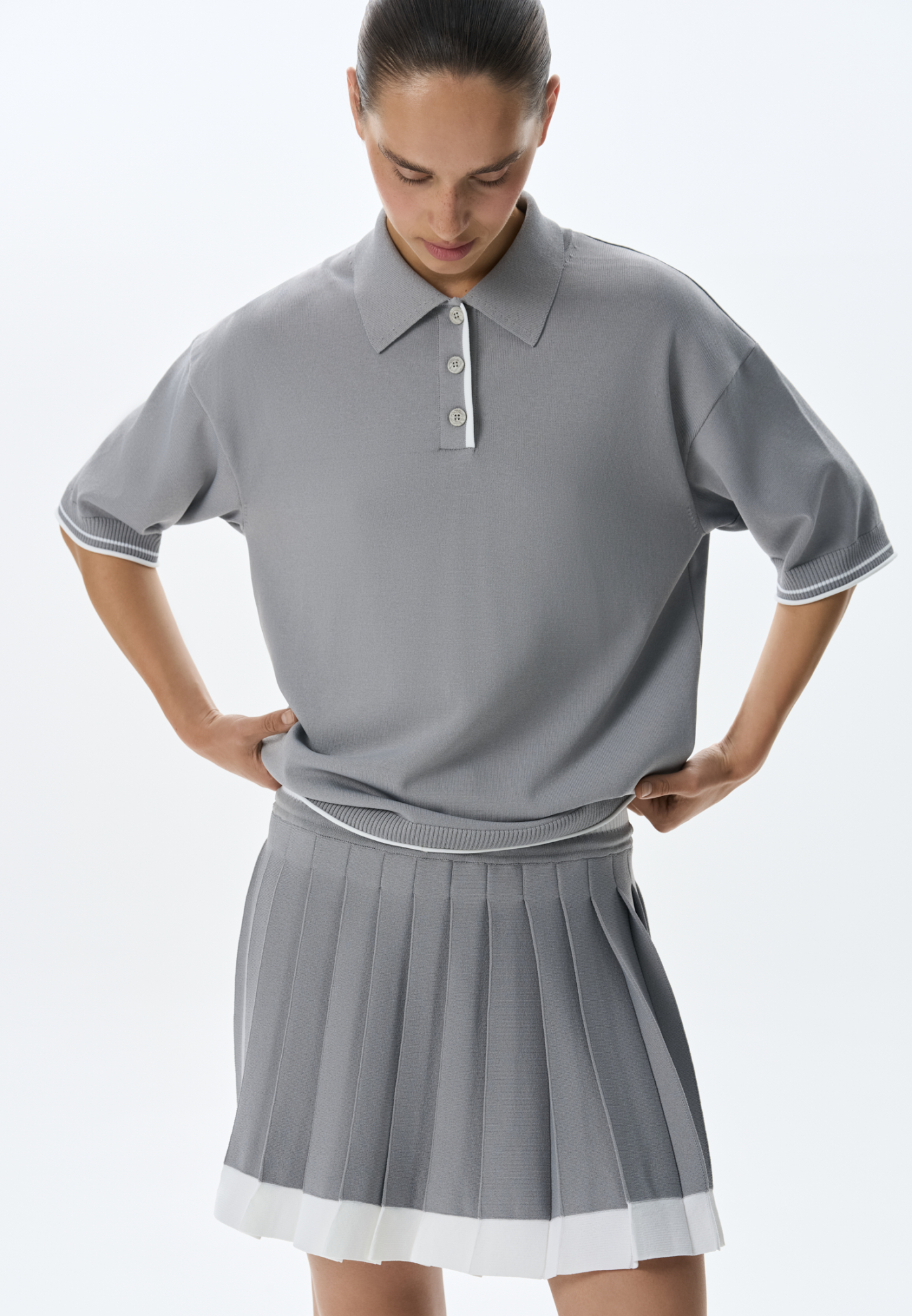 Трикотажная футболка поло из вискозы. Модель прямого силуэта, со спущенной линией плеч, короткими рукавами, отложным воротником-поло и планкой с тремя пуговицами. Рукава и нижний край изделия декорированы кантом контрастного цвета. 