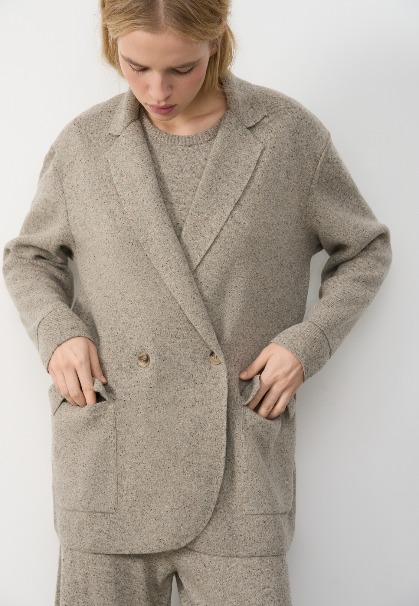 Трикотажный двубортный жакет из шерсти с добавлением вискозы и шелка. Модель прямого кроя, с лацканами, двумя накладными карманами и валиками на манжетах. Застежка на пуговицы. Без подкладки. 