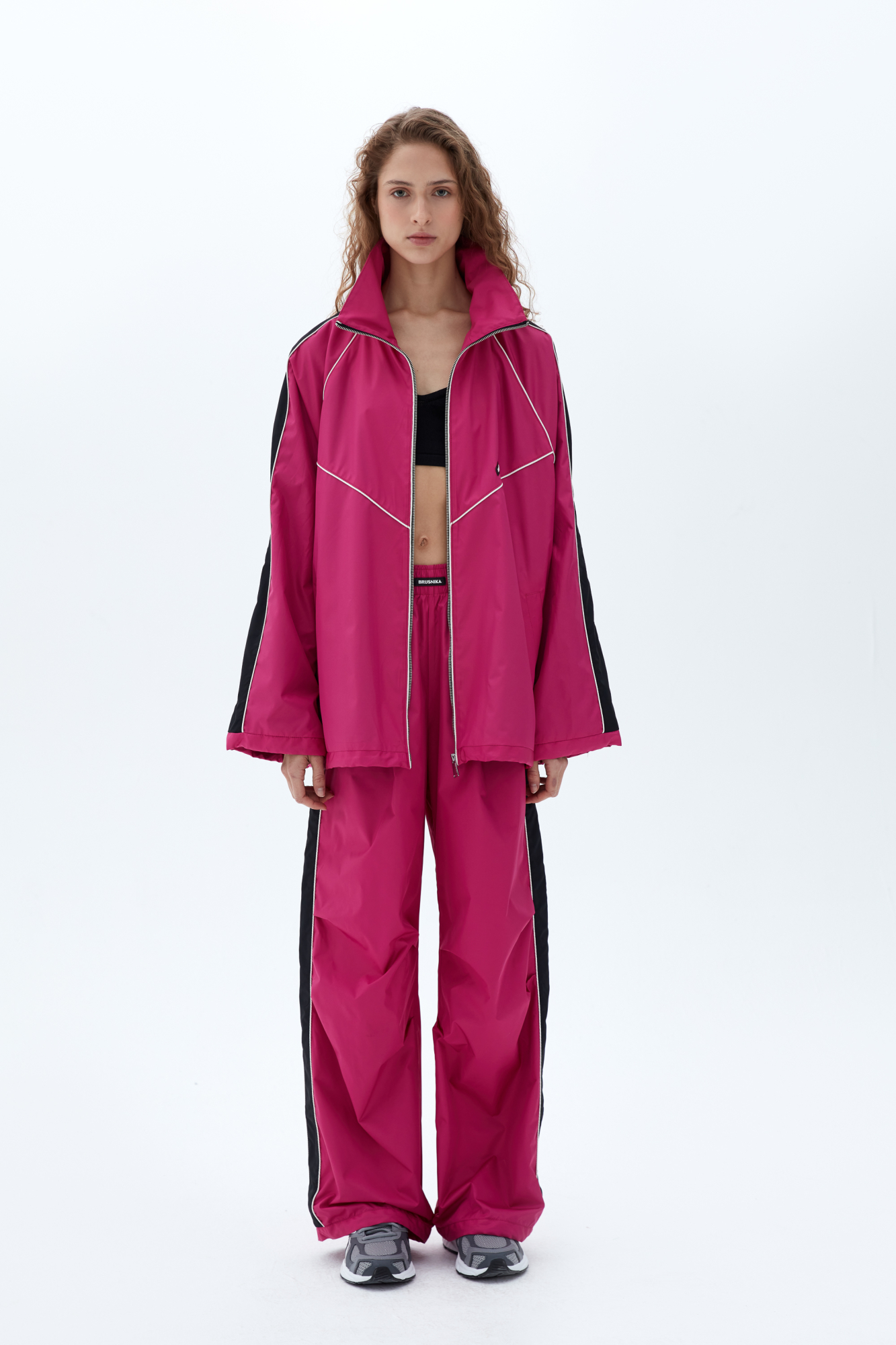 Брюки в спортивном стиле с карманами по бокам, белым кантом и широким лампасом. Пояс на эластичной ленте с брендированным ярлыком, манжеты на регулируемой кулиске. Дополнить образ можно бомбером или курткой в том же стиле.<br />