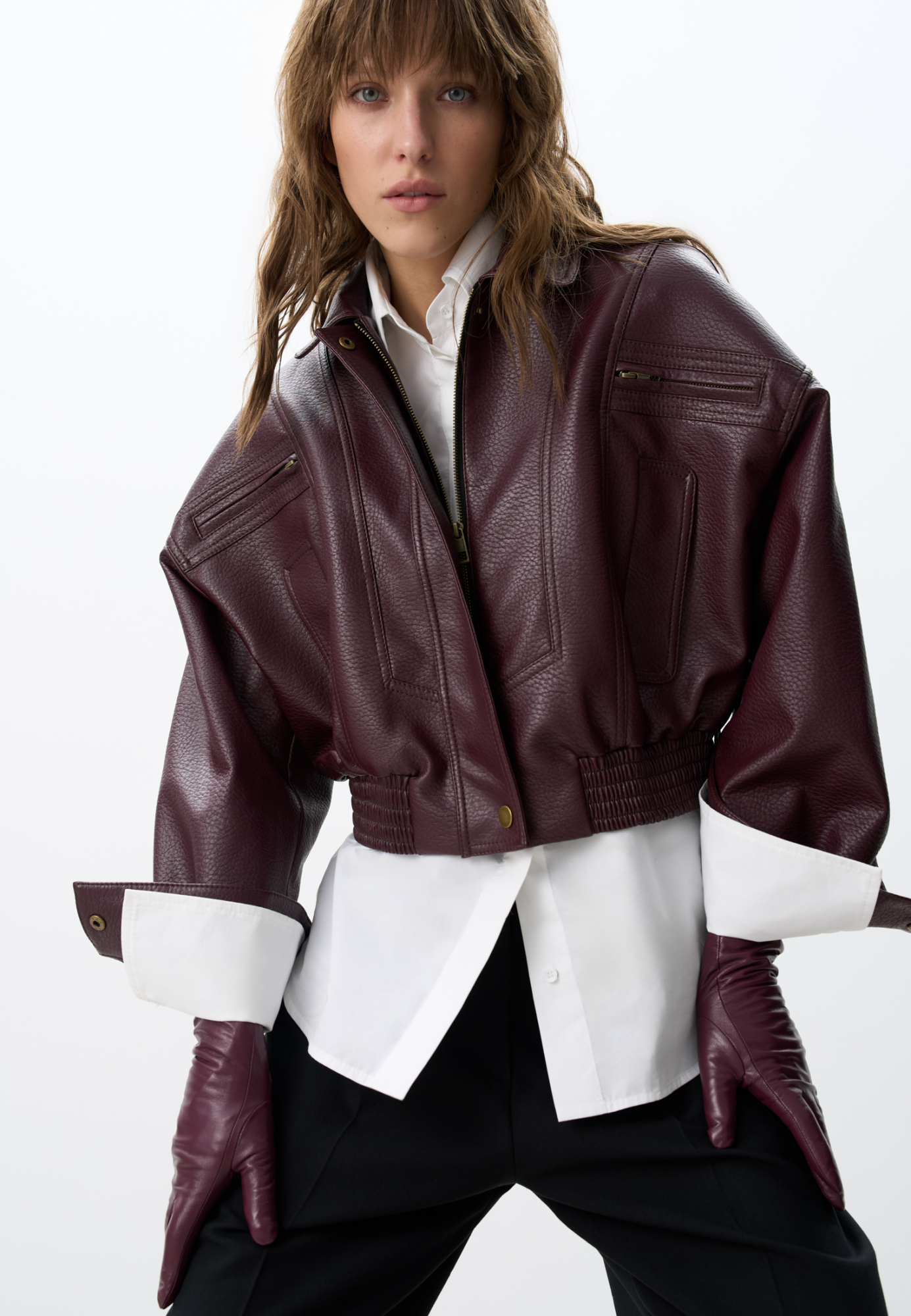 Укороченный бомбер из экокожи.Модель свободного силуэта с длинными рукавами, с воротником и двумя нагрудными карманами. Застежка на молнию. Изделие на подкладке.