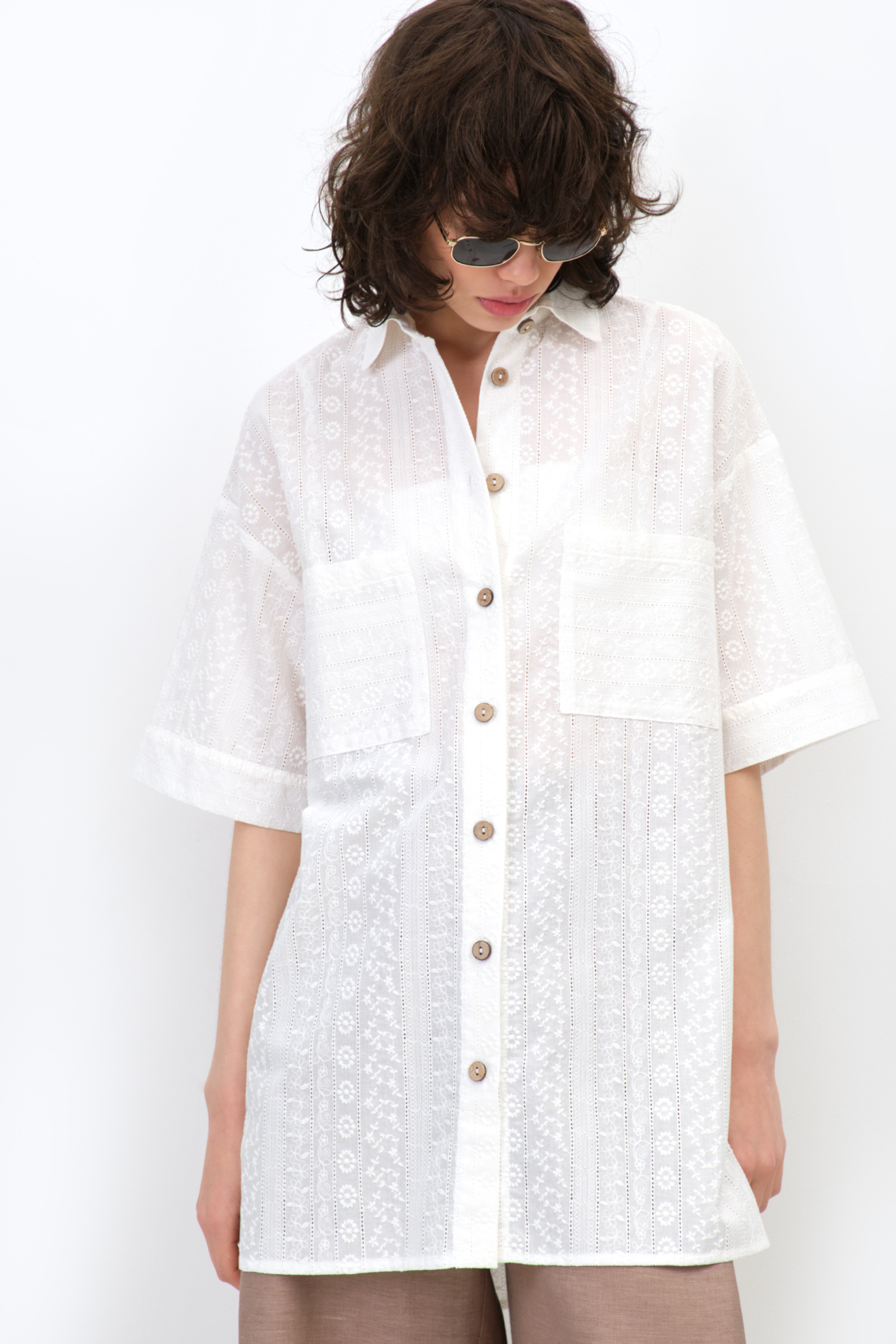 Рубашка из 100% хлопка. Модель прямого кроя, с отложным воротником и короткими рукавами. Застёгивается на пуговицы по всей длине. На груди расположены два накладных кармана. Ткань имеет текстурированную поверхность с вертикальными полосами и вышитым узором.<br />
