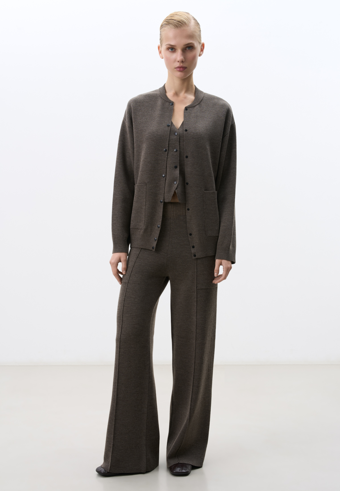 Трикотажные брюки в основе из шерсти мериноса. Модель свободного силуэта со стрелками, боковыми карманами и эластичным поясом. Дополнить образ можно комплектными жилетом и бомбером.