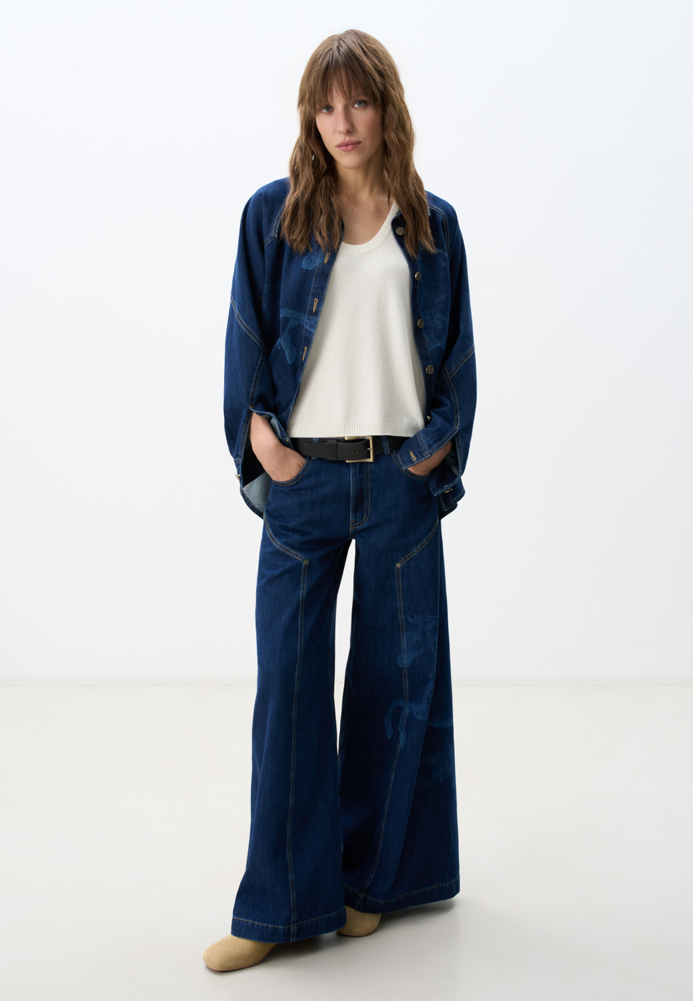 Широкие джинсы из 100% хлопка с принтом лошадей. Модель на средней посадке, с пятью карманами и шлевками на поясе для ремня. Застежка на молнию и пуговицу. На штанинах изделие декорировано принтом лошадей, выполненным лазером, и объемными геометрическими вытачками с заклепками. <br />
Модель в стиле дерби - направления в моде, которое имитирует одежду для скачек.