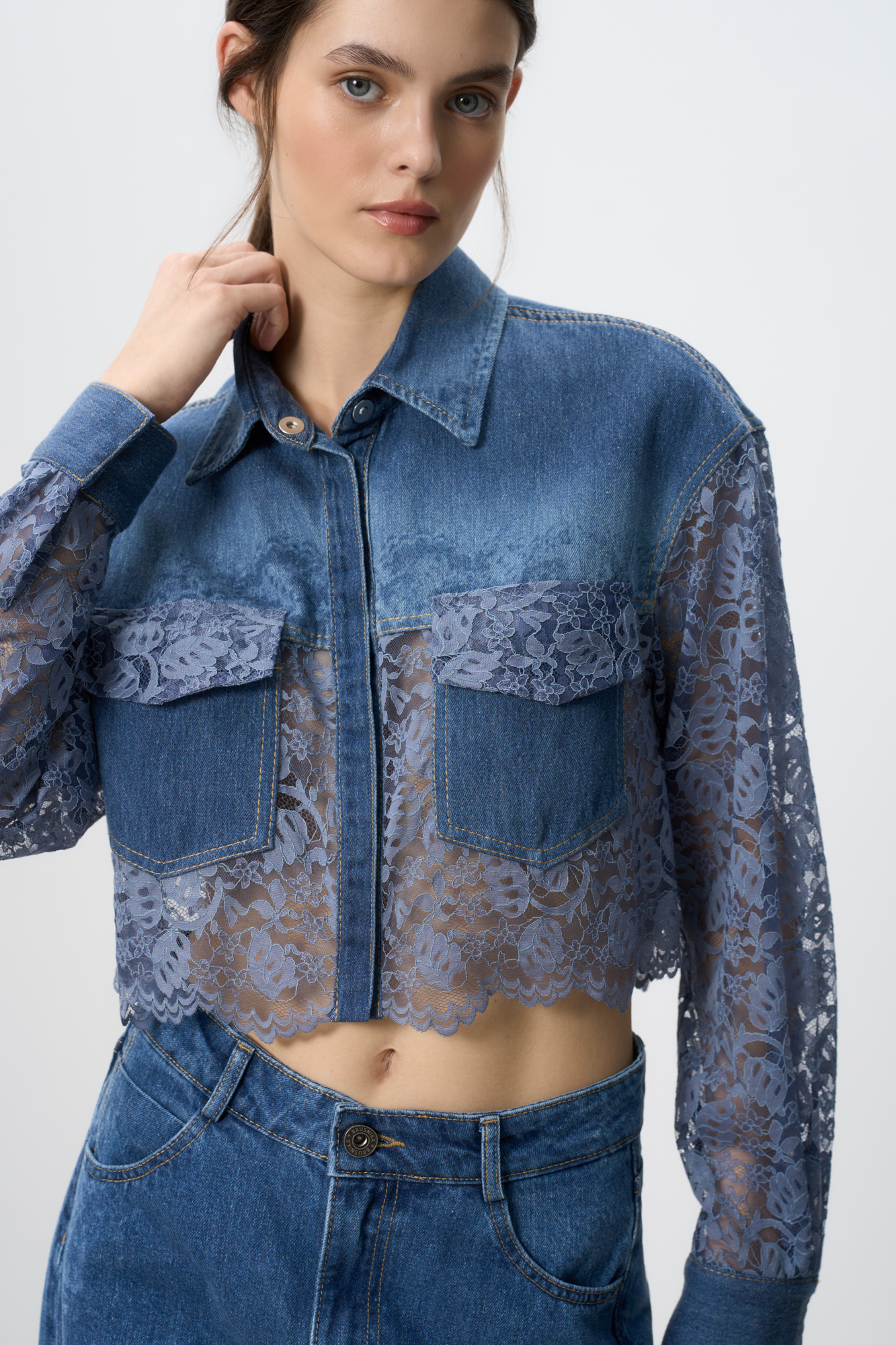 Укороченная рубашка с кружевом. Модель свободного силуэта с накладными карманами. Застежка на кнопки и пуговицу.