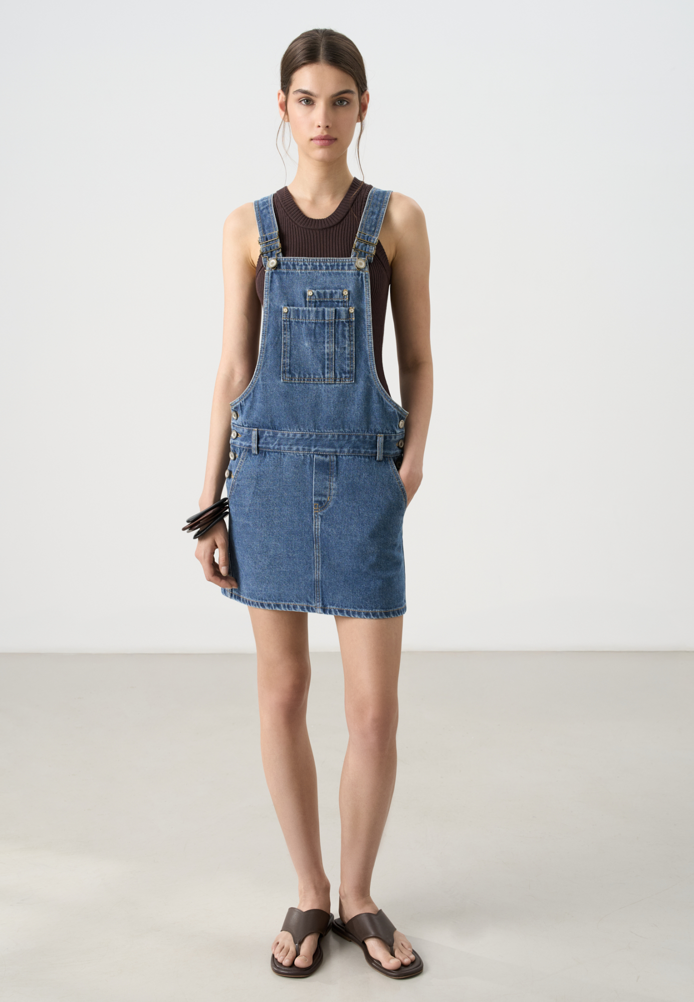 Джинсовый комбинезон из 100% хлопка. Модель с короткой юбкой, шлевками на поясе для ремня, боковыми и задними карманами.Бретели регулируются по длине.